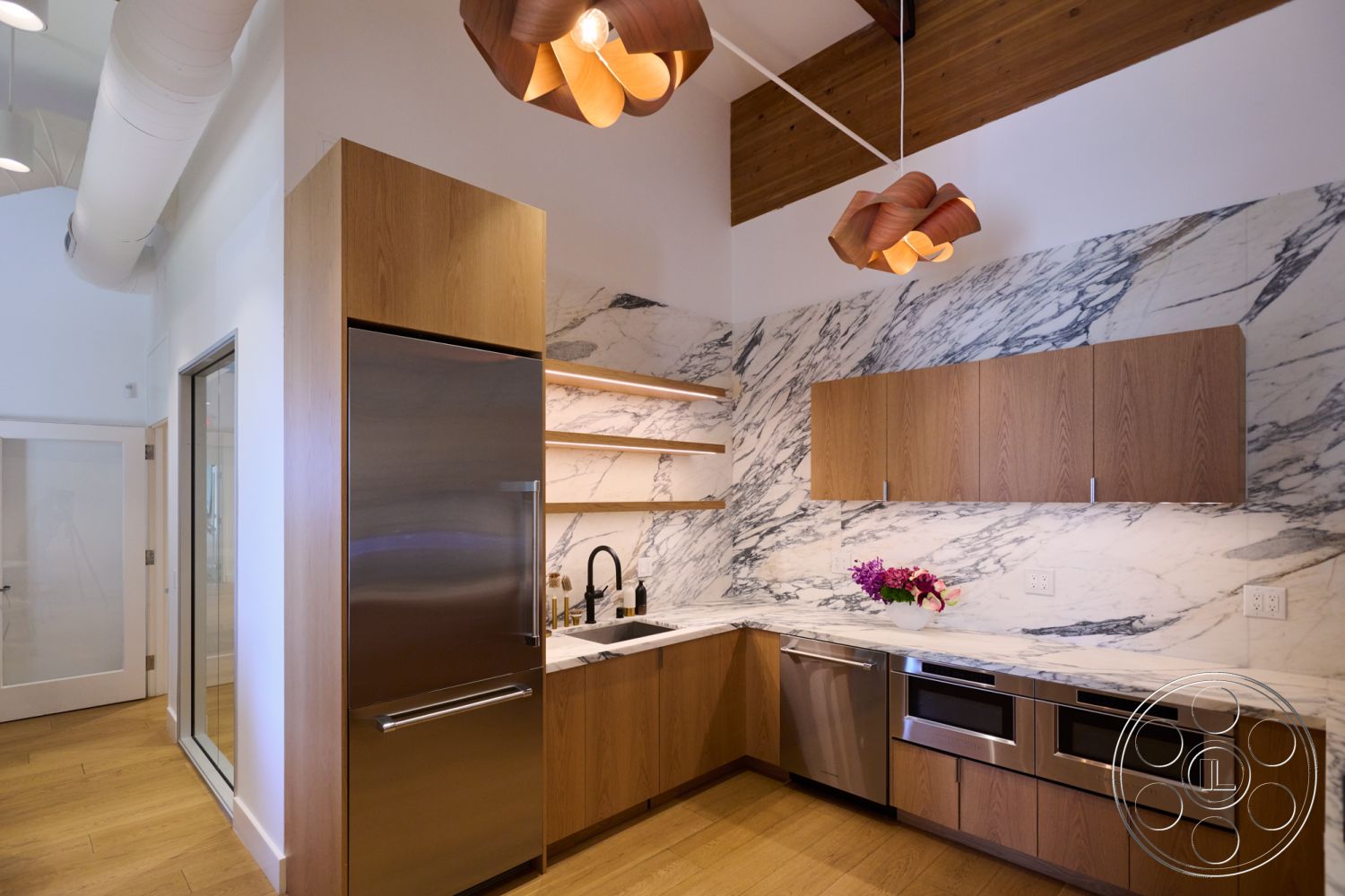 Office 129 - stainless steel refrigerator, natural light from window, exposed wood ceiling beams, contemporary kitchen aesthetic, granite kitchen countertops, stainless steel dishwasher, marble kitchen backsplash, interior kitchen with hardwood flooring, hanging pendant light fixtures, white cabinetry with wood accents, open shelving with decorative plants, modern design with sleek lines