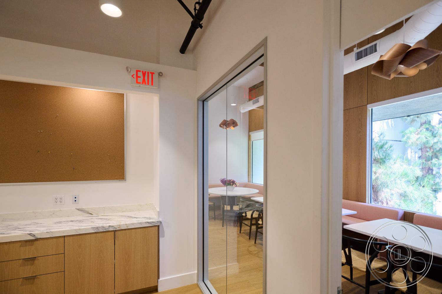 Office 129 - interior recessed lighting, interior marble countertop, interior modern pendant lighting, interior hardwood flooring, interior minimalist design, interior glass partition wall, interior oak cabinetry, interior corkboard wall, interior round table seating, interior wooden panel wall, interior exit sign detail, interior natural light windows, interior collaborative workspace, interior comfortable dining area, interior vibrant plant decor