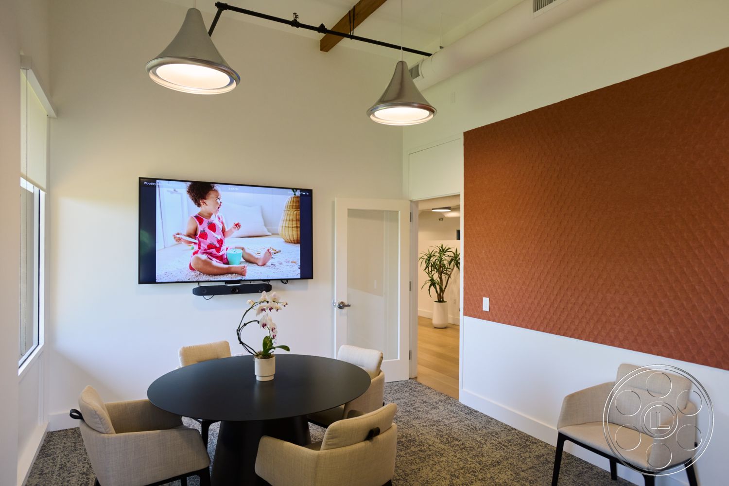 Office 129 - minimalist decor, round dining table, recessed lighting fixtures, large windows with natural light, neutral carpet flooring, interior meeting room, indoor plant decoration, faux leather wall treatment, contemporary upholstered chairs, textured acoustic wall panel, modern flat-screen TV, open door design