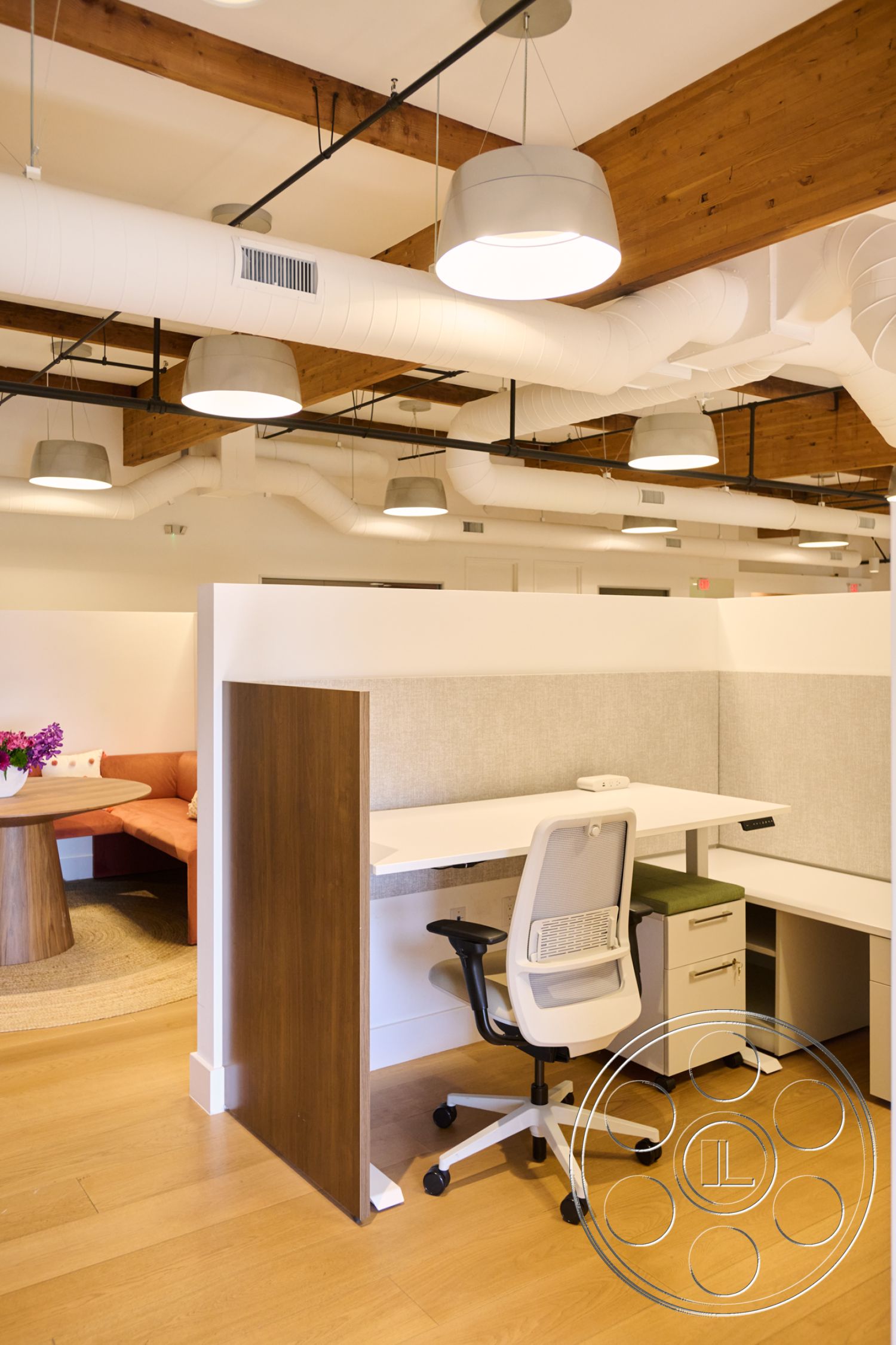 Office 129 - neutral color palette, hanging pendant lights, open office layout, exposed wood ceiling beams, commercial interior design, modern ergonomic office chair, textured fabric wall panels, wood laminate office flooring, cubicle wall partitions, contemporary office workstation, collaborative lounge seating, round wooden conference table, light-filled workspace with floor-to-ceiling windows, industrial style ductwork, cozy break area with plush seating