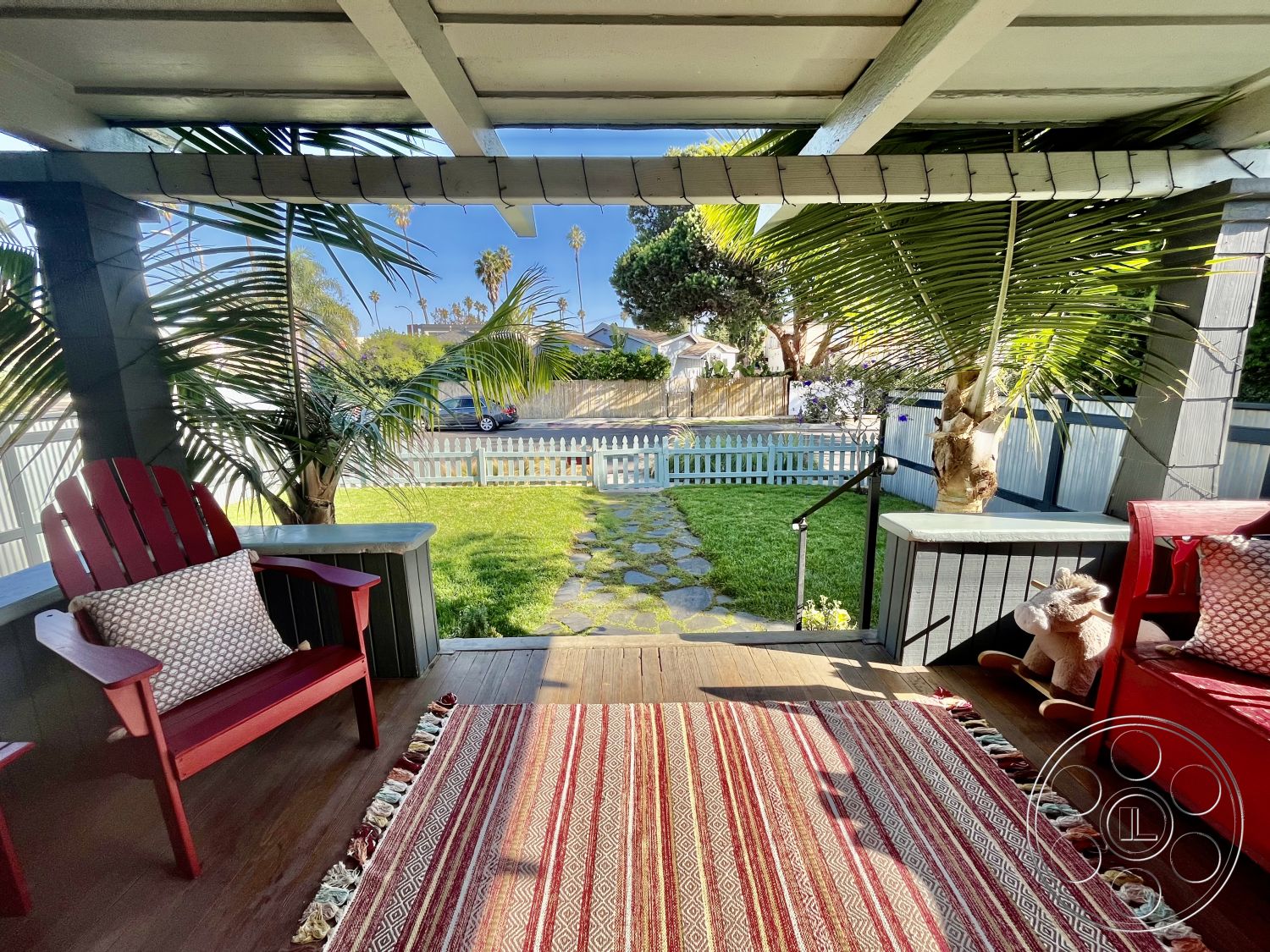 Craftsman 56 - textured area rug, garden view, outdoor seating area, stone pathway, white picket fence, tropical palm trees, green grass lawn, sunny outdoor setting, interior living room, red adirondack chairs, wooden porch floor, exterior covered patio, wood railing with decorative post, traditional decor elements