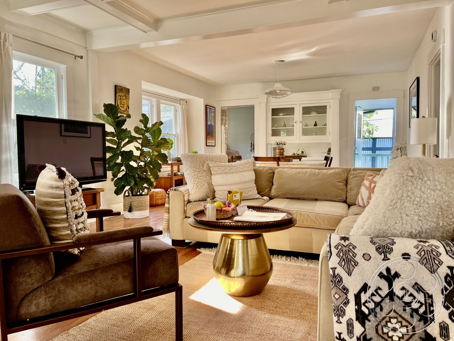 Craftsman 56 - neutral color palette, textured area rug, modern coffee table, decorative throw pillows, indoor plant decor, tan sectional sofa, exposed wood ceiling beams, hardwood living room floors, open floor plan layout, mid-century modern design elements, white painted walls, large windows with sheer curtains, natural lighting interior, minimalist TV stand, glass cabinet with decorative items