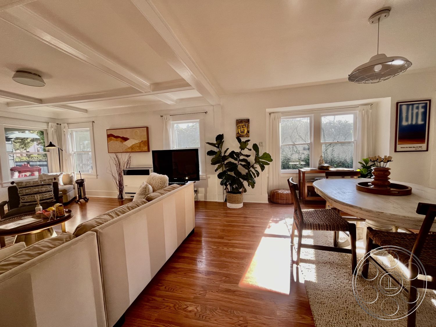 Craftsman 56 - neutral color palette, textured area rug, open concept layout, sunlit ambiance, inviting seating area, ambient lighting fixtures, exposed wood ceiling beams, interior living space, hardwood living room floors, white painted walls, modern sectional sofa, large windows with natural light, elegant light fixture, coffered ceiling design, wood dining table with woven chairs, decorative wall art accents, indoor planter with greenery, minimalist television unit