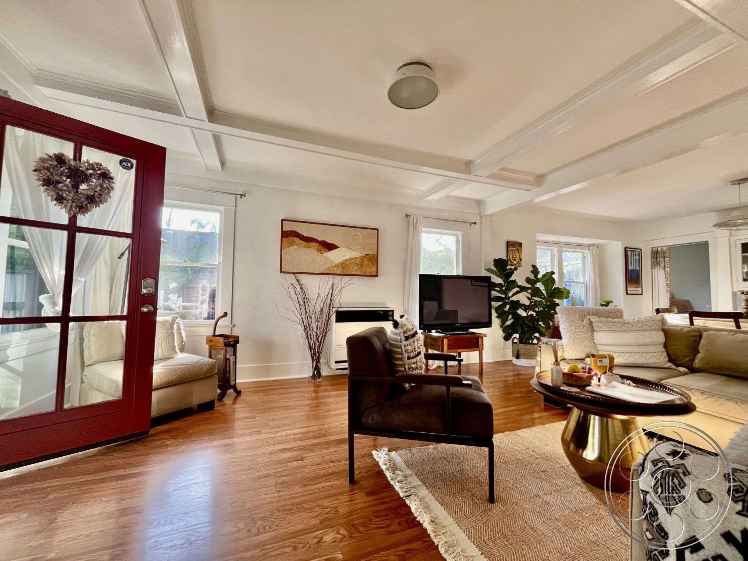 Craftsman 56 - interior coffered ceiling details, interior hardwood living room floors, interior natural light from windows, interior potted plant decor, interior white painted walls, interior round coffee table, interior upholstered sectional sofa, interior warm color palette, interior decorative wall art, interior minimalist decor style, interior glass door entrance, interior upholstered armchair, interior textured throw blanket, interior sheer window curtains, interior neutral area rug