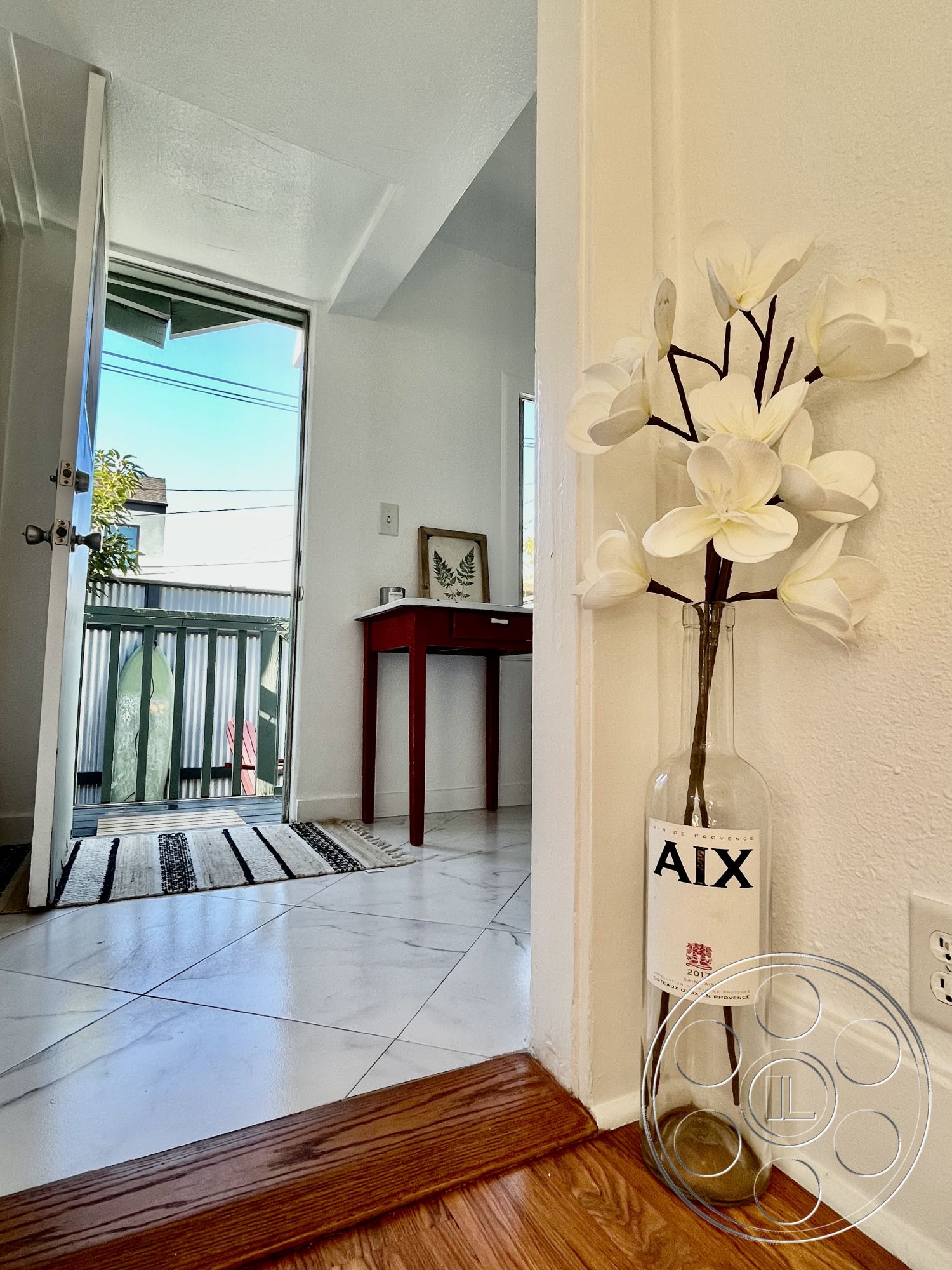 Craftsman 56 - interior natural light, interior white painted walls, interior plant decor, exterior glass sliding doors, interior marble tile flooring, interior patterned area rug, interior hardwood entryway flooring, interior exposed wood door frame, interior decorative flower vase, interior minimalistic wooden accent table, interior bright open entryway