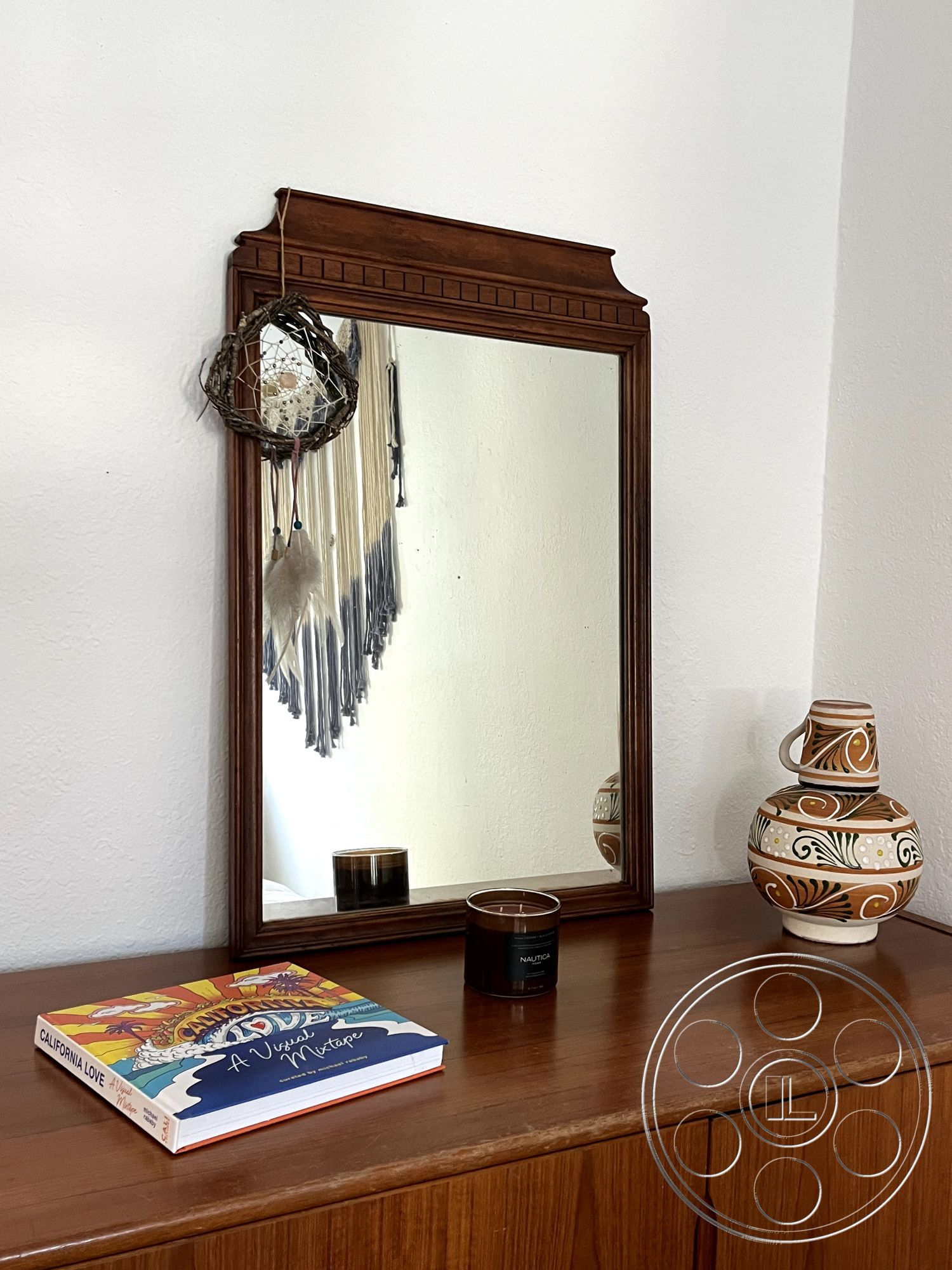 Craftsman 56 - soft natural light, textured wall treatment, decorative wall hanging, casual living space, wooden mirror frame, natural wood dresser, ceramic vase with intricate designs, coffee table book on top of dresser, scented candle on dresser, interior decor accents, neutral interior color palette, modern bohemian style, cozy interior setting