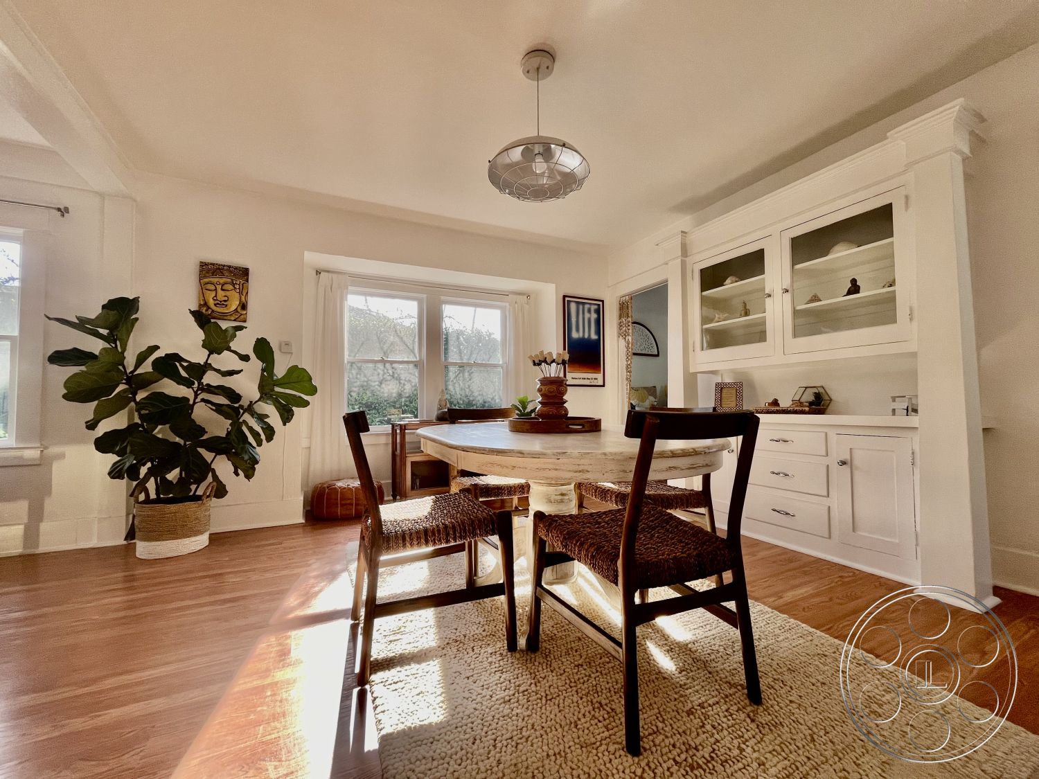 Craftsman 56 - glass display cabinets, round wooden dining table, woven dining chair, interior dining area, modern pendant light fixture, open floor plan layout, white painted walls, large windows with natural light, hardwood dining room floors, contemporary wall art, traditional crown molding details, potted indoor plant, woven accent area rug