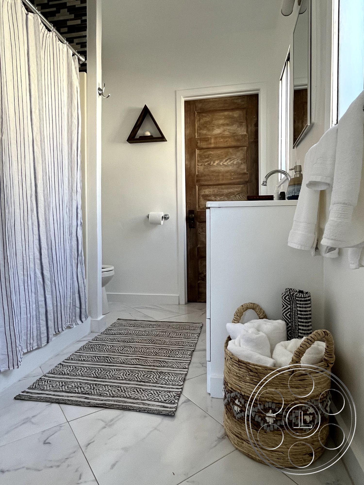 Craftsman 56 - neutral color palette, woven storage basket, interior bathroom, chrome faucet fixtures, compact bathroom layout, textured white painted walls, modern rectangular mirror, rectangular porcelain tile flooring, striped fabric shower curtain, wooden door with natural finish, decorative bath rug with geometric pattern, white towels in storage, bathroom with minimalist design, slim toilet with modern design, triangular wall shelf