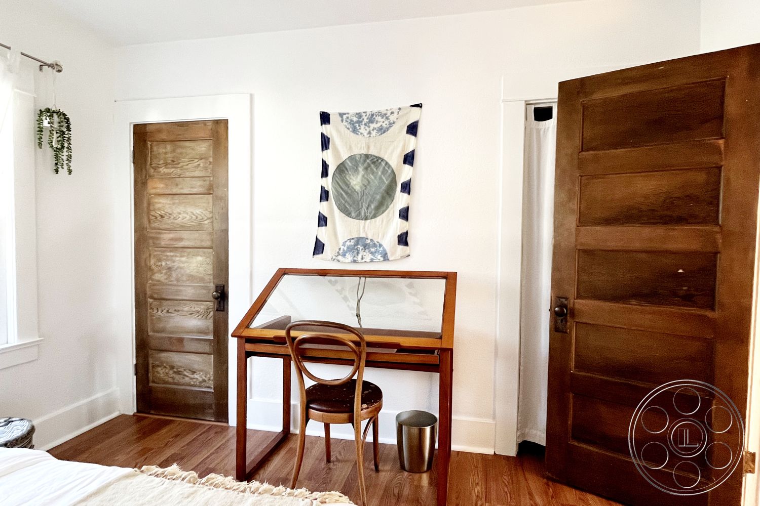 Craftsman 56 - natural lighting, cozy ambiance, small study area, textured wall hanging, glass window treatments, minimalist interior design, hardwood bedroom floors, neutral painted walls, wood panel door, wooden desk with glass top, simple dining chair