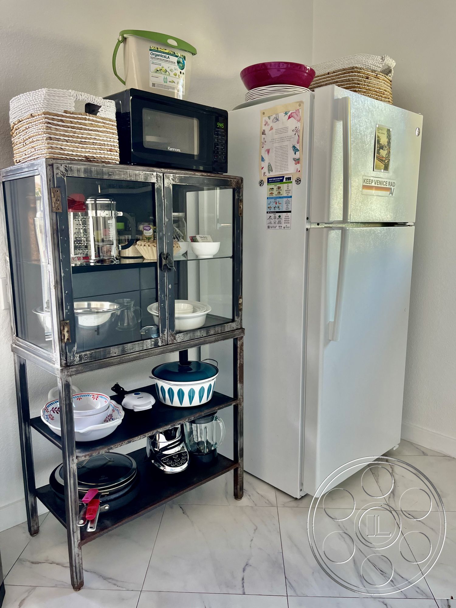 Craftsman 56 - woven storage baskets, glass display cabinet, stainless steel refrigerator, decorative kitchen accessories, modern kitchen appliances, interior kitchen space, minimalist kitchen design, functional kitchen storage, open layout kitchen, ceramic dishware display, black microwave oven, metal frame kitchen shelving, white marble tile floors, blue and white patterned bowl, glass water pitcher