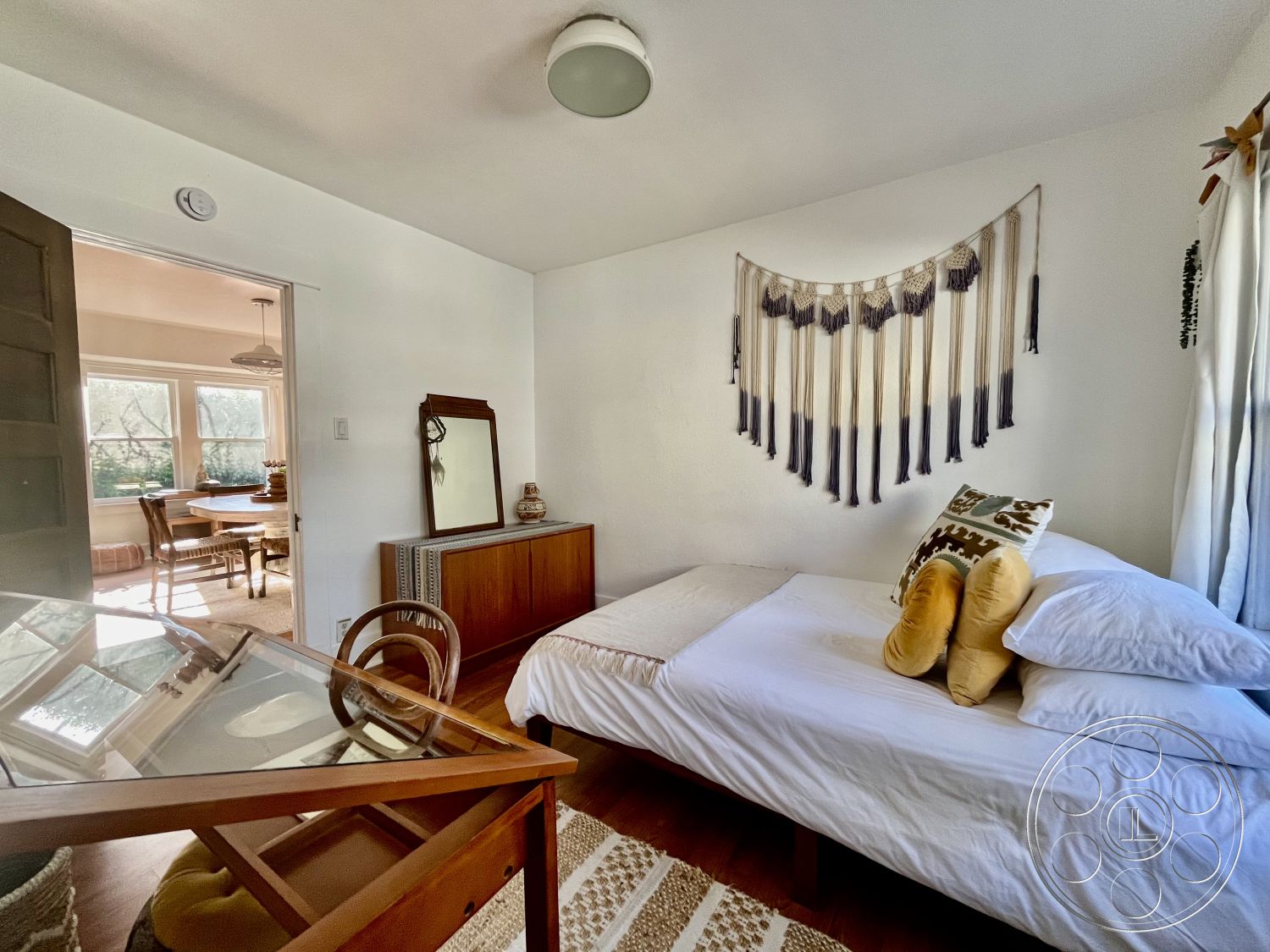 Craftsman 56 - minimalistic design, natural light from window, contemporary interior, wood dresser, glass mirror, cozy bedroom setting, hardwood bedroom floors, white painted walls, macrame wall art, soft texture accent pillows