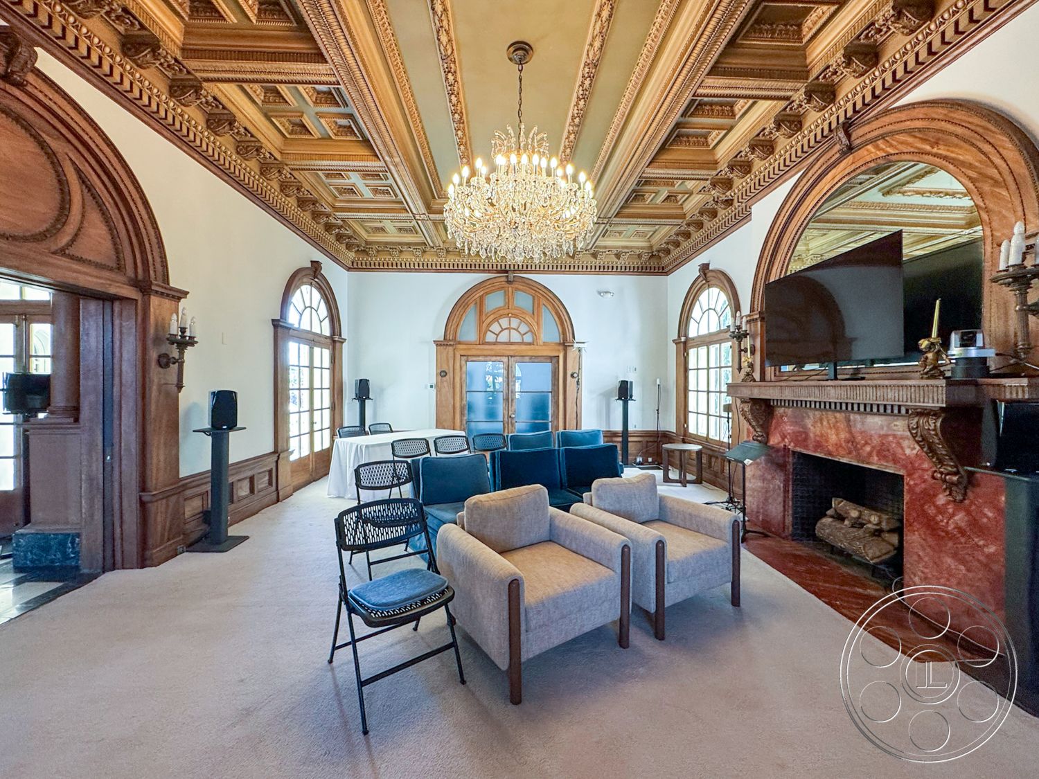 Adams Mansion - high ceilings, open floor plan, gathering space, arched doorways, decorative wall sconces, soft color palette, stylish accent chairs, chandelier light fixture, classic architectural style, elegant crown molding, modern sectional sofa, marble fireplace surround, coffered ceiling details, decorative baseboards, rich wood finishes, hardwood paneling walls, luxurious carpet flooring, large windows with wood frames