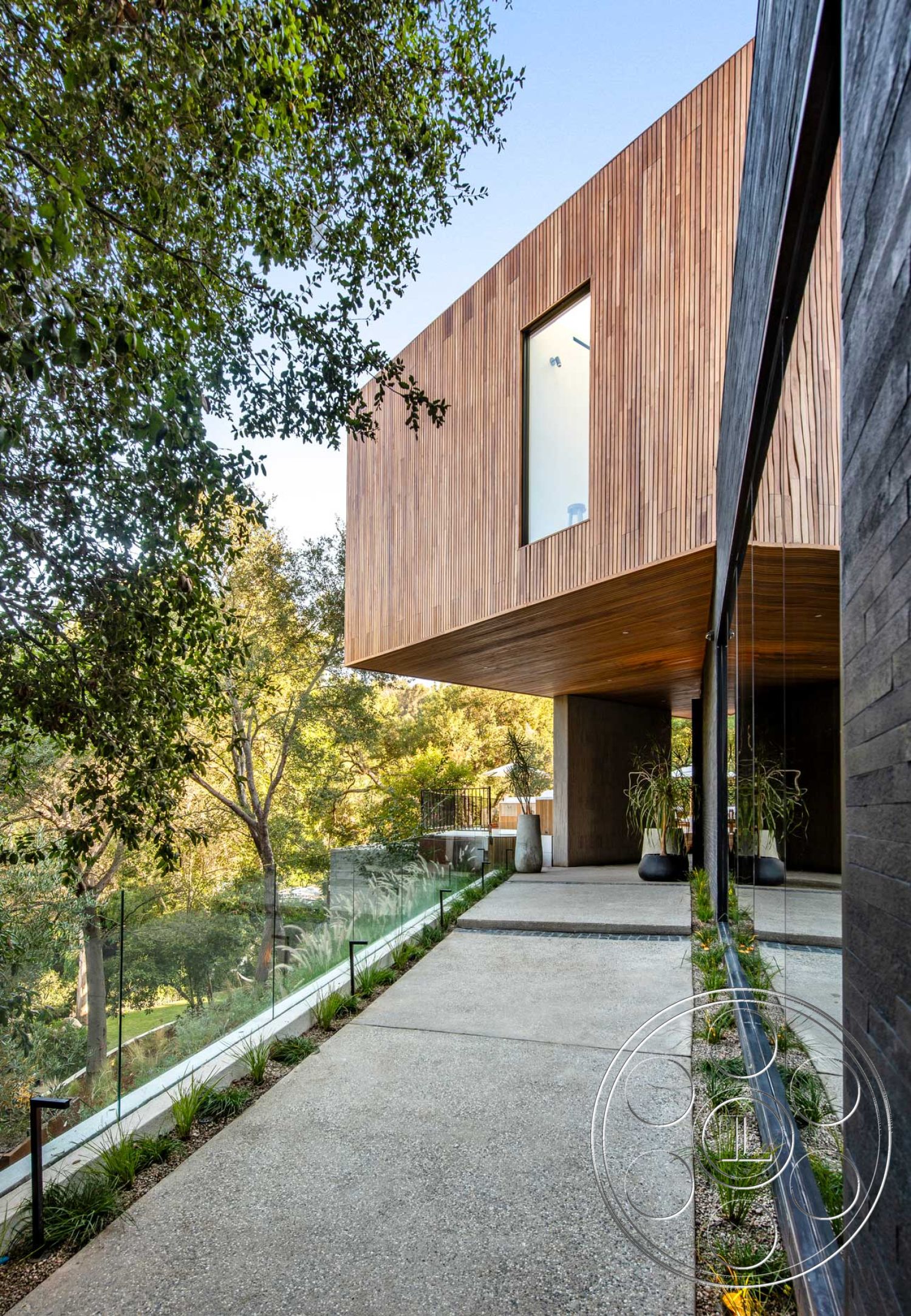 Modern 520 - exterior, minimalist aesthetic, glass railing, floor-to-ceiling windows, modern architectural style, open outdoor space, concrete walkway, surrounded by trees, smooth concrete finish, natural light emphasis, landscaped garden borders, wood paneling facade, overhang roof detail, integrated planter pots, veranda with wooden accents