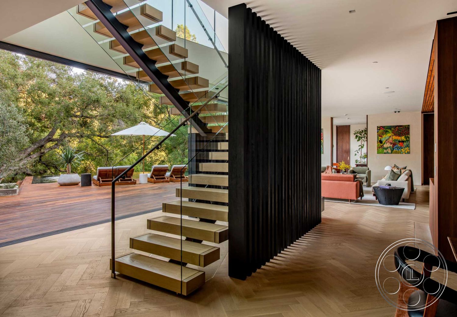 Modern 520 - floor-to-ceiling windows, sustainable design elements, ambient lighting fixtures, contemporary architectural style, artwork on wall interior, smooth plaster walls interior, wood herringbone flooring interior, glass railing staircase interior, floating staircase with wood treads, black vertical slat partition wall interior, open concept living area with natural light, modern furnishings in living room, outdoor deck with wooden lounge chairs, landscaped garden view from interior, minimalist interior design style, elegant dining space adjacent to living area