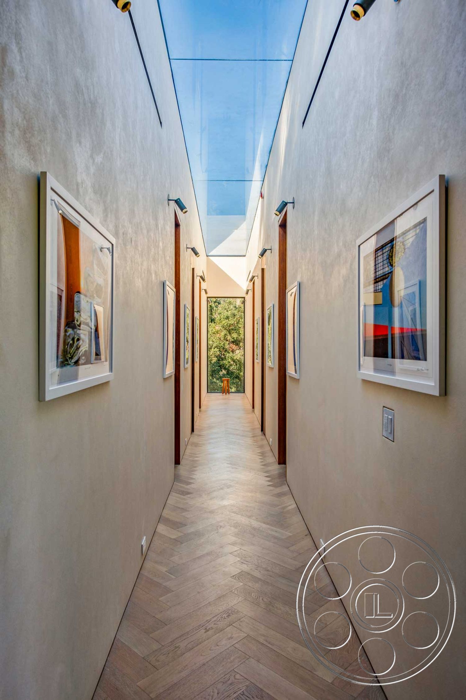 Modern 520 - neutral color palette, natural light, narrow corridor, plastered walls, contemporary interior design, glass skylight, modern minimalist style, wooden door frames, herringbone hardwood flooring, framed artwork on walls, ceiling-mounted light fixtures, open view to garden