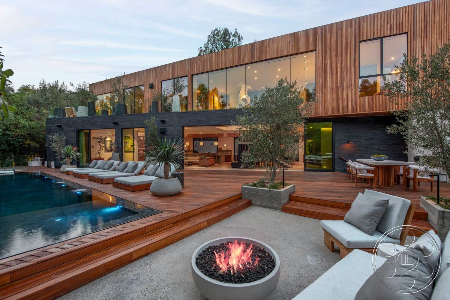 Modern 520 - exterior, landscaped garden, large glass sliding doors, rectangular swimming pool, floor-to-ceiling windows, open concept living space, concrete pool deck, hardwood deck, outdoor entertaining area, modern lounge chairs, contemporary architectural style, fire pit with decorative stones, comfy outdoor seating, wooden exterior paneling, black stone wall, lush greenery surrounding pool area, circular outdoor dining table, sunny daytime setting, urban residential backyard