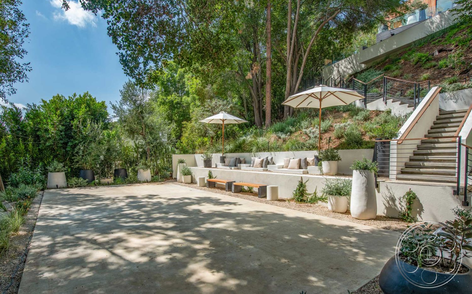 Modern 520 - wooden bench seating, textured wall treatments, contemporary outdoor design, concrete patio flooring, exterior patio area, minimalist outdoor seating, landscaped hillside setting, surrounding trees and foliage, planter boxes with greenery, natural stone garden features, stainless steel railing details, modern umbrella shading, steps with metal accents, artful stone planters, open air entertaining space, garden-style environment