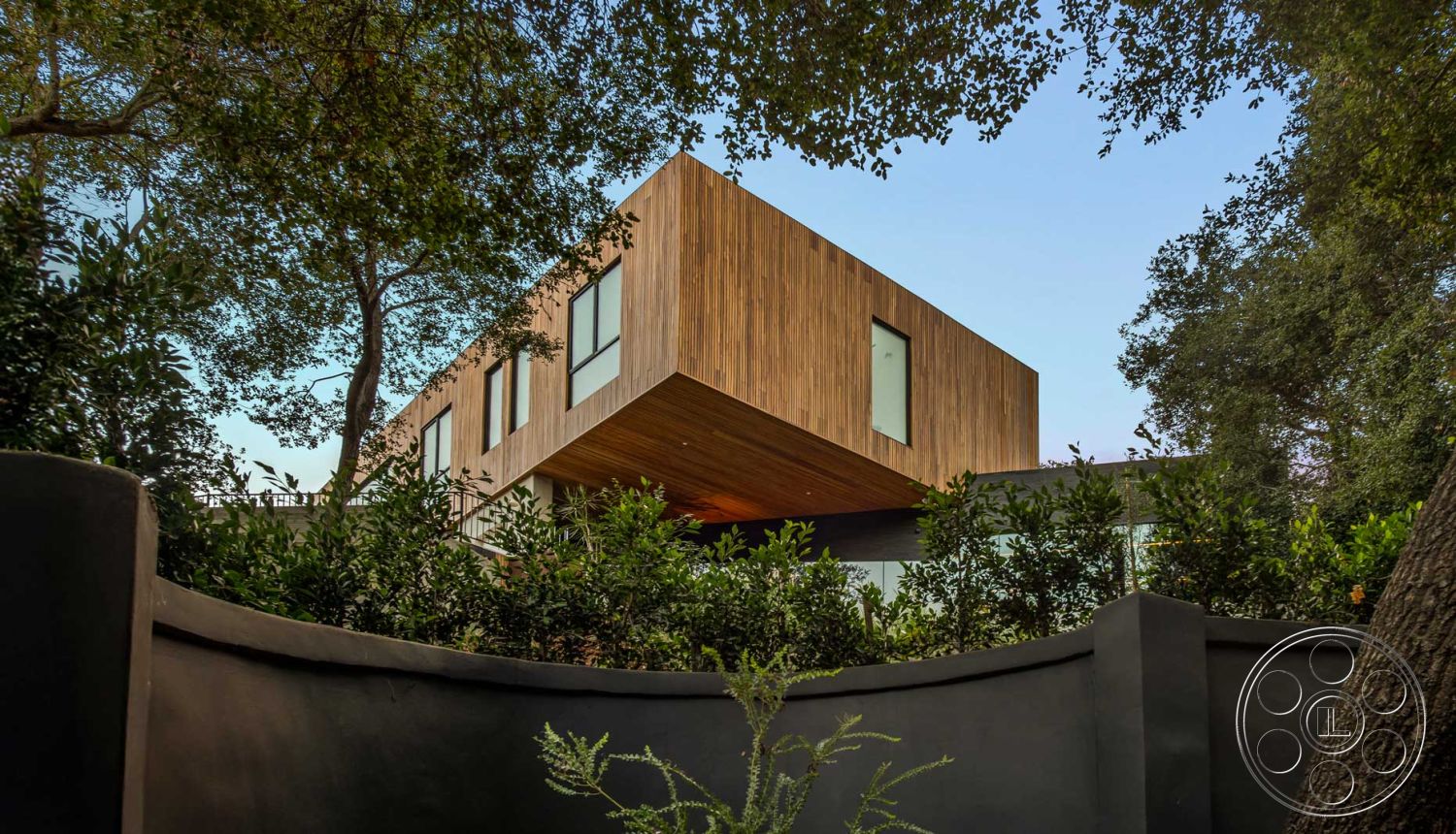 Modern 520 - open space layout, minimalist design elements, floor-to-ceiling windows, modern architectural style, exterior concrete wall, rectangular window shapes, exterior wood siding, floating wooden overhang, angular roof line, landscape greenery surround, set in wooded environment, textured gray concrete base, staggered facade design