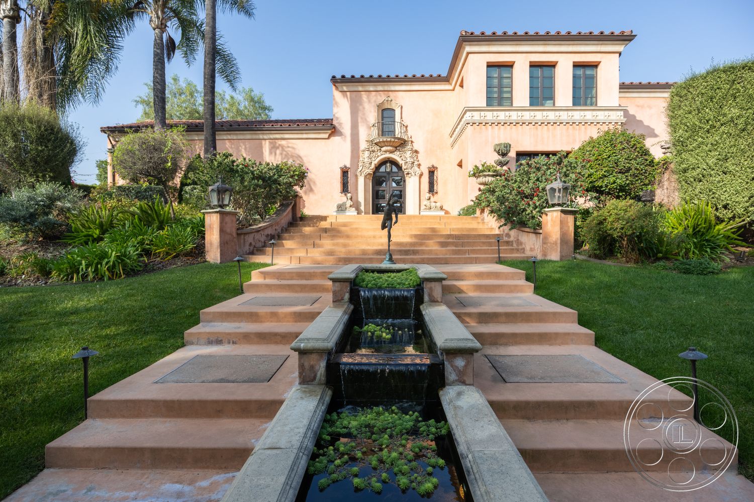 Mansion 145 - concrete steps, lush green lawn, arched doorways, ornamental lanterns, landscaped garden area, concrete patio flooring, exterior stucco walls, decorative stone accents, two-story Mediterranean home, lush tropical plants, tranquil garden setting, ornate wrought iron railings, symmetrical façade design, paved garden pathway, tiled roof with terracotta tiles, elegant fountain feature, morning light ambiance, structured stairway with landings, exterior window shutters, planted shrubs and hedges