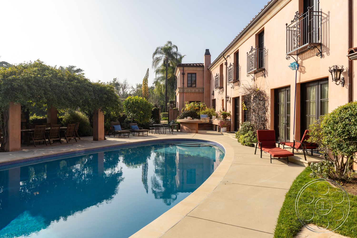 Mansion 145 - rectangular swimming pool, concrete pathway, outdoor dining area, contemporary outdoor lighting, arched doorways, concrete pool deck, indoor-outdoor living, multiple seating areas, poolside lounging area, lush garden setting, stone patio flooring, palm tree landscaping, stucco building facade, exterior pool area, wrought iron balcony railing, modern outdoor lounge chairs, wooden dining furniture, sunny backyard retreat, low-maintenance greenery