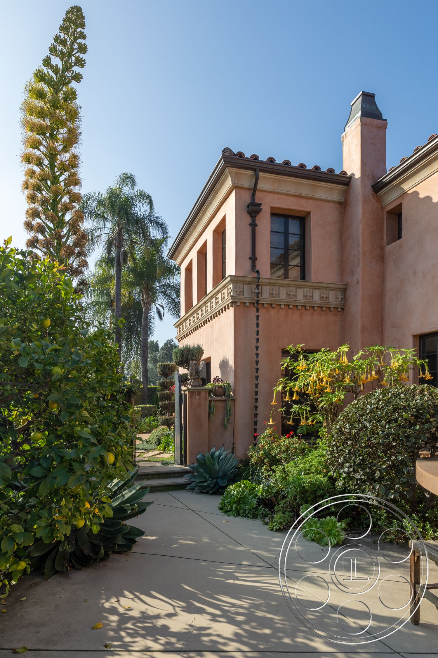 Mansion 145 - exterior, natural stone accents, stucco walls, arched windows, coastal palm trees, hillside location, clay tile roof, integrated landscaping, flagstone pathway, decorative wall lanterns, lush green foliage, open outdoor seating area, mediterranean architectural style, courtyard entryway, tropical garden setting, ornate stone trim, textured plaster finishes, climbing plants on trellis, built-in garden planters, large format outdoor tiles