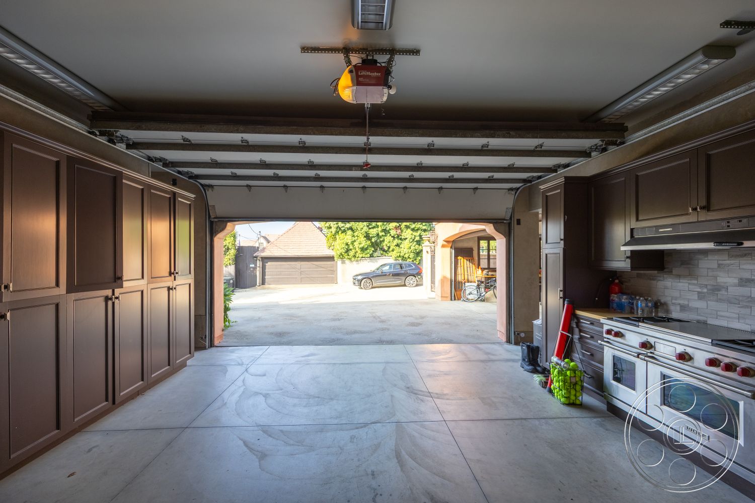 Mansion 145 - dark wood cabinetry, stainless steel appliances, storage cabinets, high ceiling, urban setting, exposed ceiling beams, open garage door, concrete garage floor, contemporary garage layout, tile kitchen backsplash, interior garage space, modern garage design, outdoor driveway view