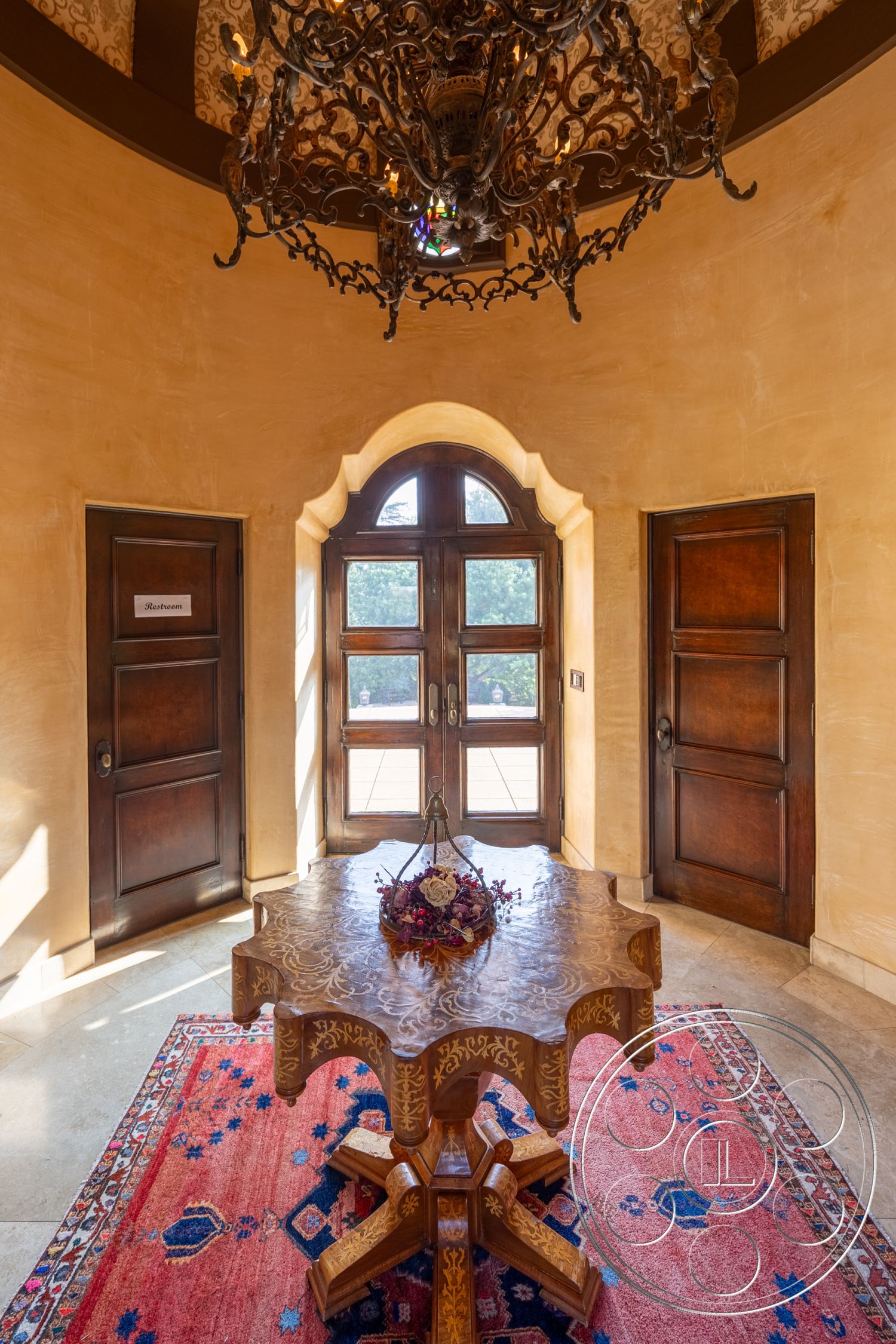 Mansion 145 - arched doorway interior, crown molding details interior, exposed plaster walls interior, marble floor tiles interior, wooden carved table interior, intricate chandelier lighting interior, double wooden doors interior, Oriental area rug interior, decorative floral centerpiece on table interior, circular ceiling design interior, rustic decor accents interior, soft natural light interior, luxurious entryway interior, traditional architecture style interior, welcoming foyer area interior