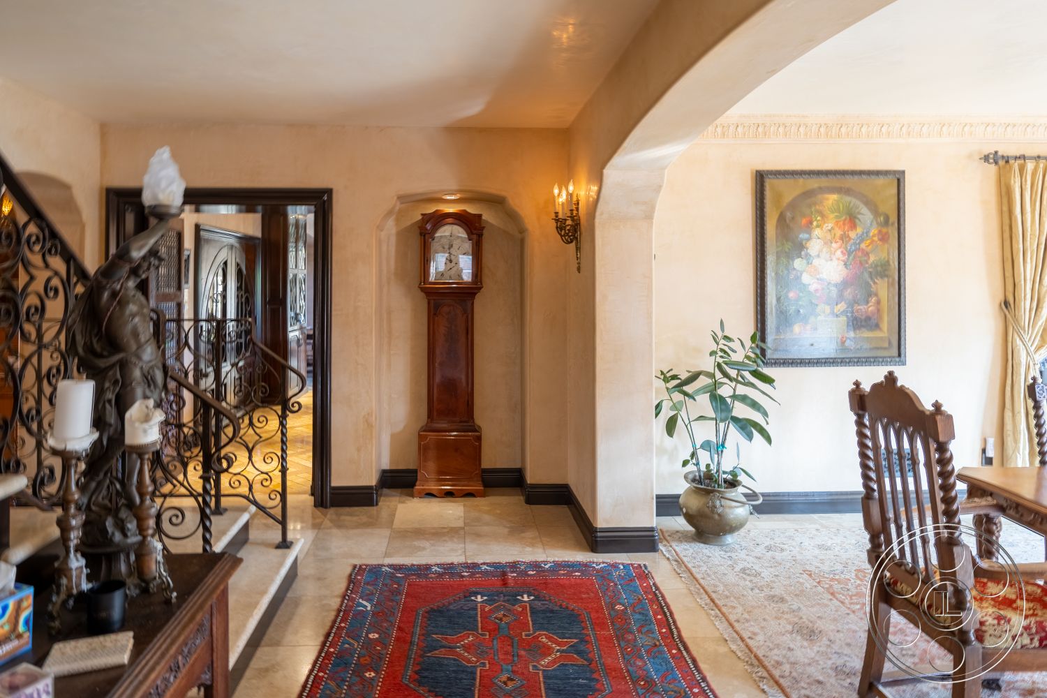 Mansion 145 - arched doorways, textured plaster walls, area rug with intricate patterns, spacious entryway, ornate wrought iron railing, crown molding details, framed floral artwork, potted indoor plant, tile entrance flooring, neutral colored walls, chandelier lighting fixtures, wooden dining room table, antique grandfather clock, traditional wooden chair, classic home office, luxurious decor accents