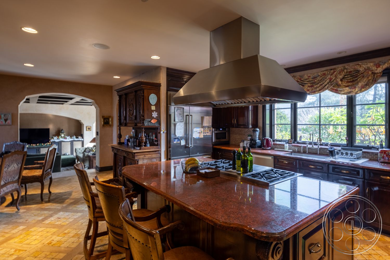 Mansion 145 - stainless steel range hood, textured plaster wall treatment, exposed wooden ceiling beams, large windows providing natural light, arched doorway leading to living space, interior kitchen with granite countertops, tile flooring with a mosaic pattern, modern kitchen island with built-in cooktop, dark wood cabinetry with intricate detailing, luxurious dining area with antique furniture, mediterranean style kitchen design, open layout connecting kitchen and dining area, brass hardware accents on cabinetry, stylish window treatments with floral patterns, cozy breakfast nook by the window, well-appointed pantry integrated into design