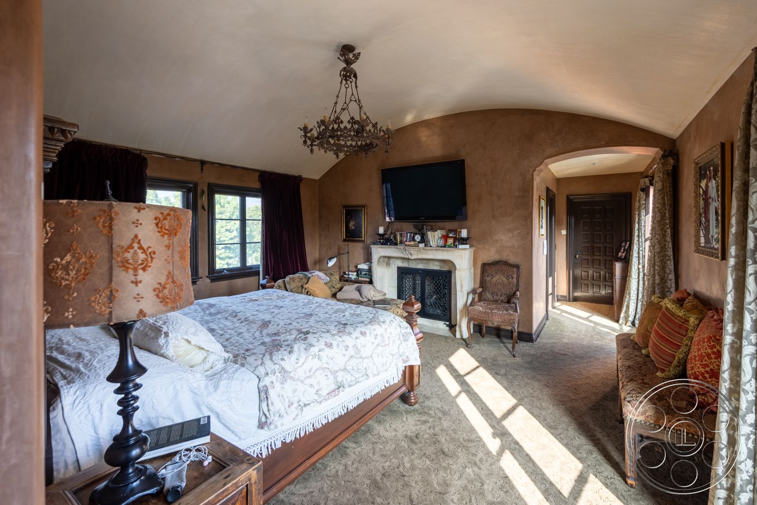 Mansion 145 - hardwood flooring interior, textured plaster walls interior, master bedroom interior, carpet flooring interior, decorative throw pillows interior, vaulted ceiling interior, arched doorway interior, cozy reading nook interior, stone fireplace surround interior, traditional chandelier lighting interior, dark wood trim interior, red velvet curtains interior, antique wood furniture interior, framed artwork details interior, side table with lamp interior