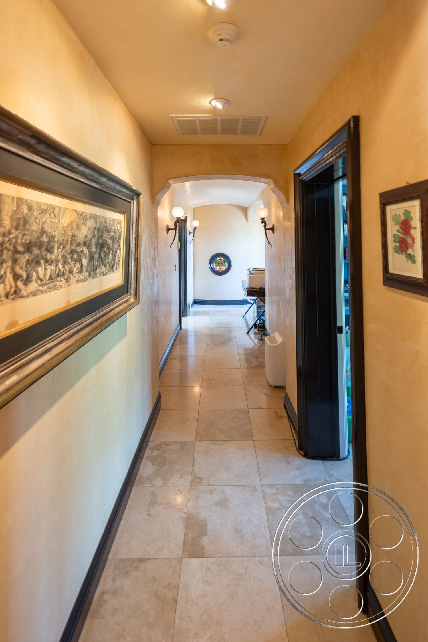 Mansion 145 - neutral color palette, open floor plan, archway entrance, recessed lighting fixtures, interior hallway, textured plaster wall treatment, polished marble floor tiles, framed artwork on walls, dark wood trim details, elegant wall sconces, decorative circular mirror, access to rooms on both sides