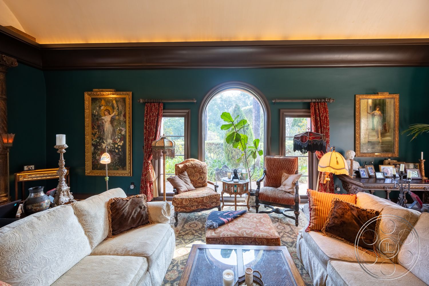 Mansion 145 - textured area rug, gold-framed artwork, interior living room, indoor potted plant, crown molding ceiling details, dark green painted walls, modern glass light fixtures, ornate vintage furniture, plush fabric couch with decorative pillows, wooden coffee table with glass top, tall arched windows, wooden accent chair with plush upholstery, classic chandelier lighting, floor lamp with fabric shade, red velvet curtains, antique side table, decorative picture frames, luxurious patterned upholstery, elegant vintage lamp, visibly manicured landscape outside