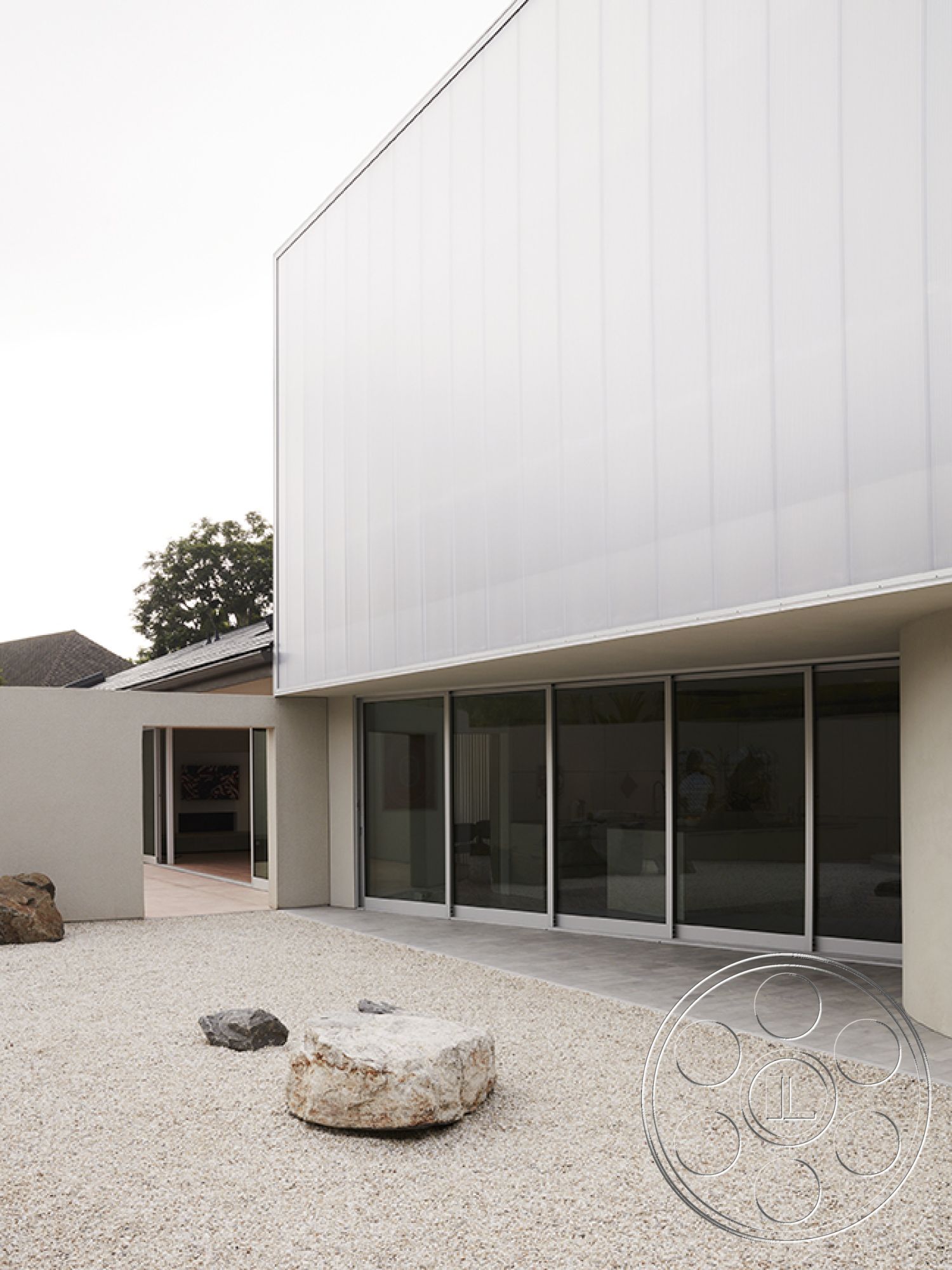 Modern 521 - glass sliding doors, modern architectural style, expansive outdoor space, landscaped garden area, white stucco wall finish, exterior stone landscaping, flat roof profile, crushed gravel patio, metal panel cladding, smooth concrete porch surface, minimalistic courtyard design, natural rock garden features, open floor plan connection, corner glazing windows, focal boulder feature