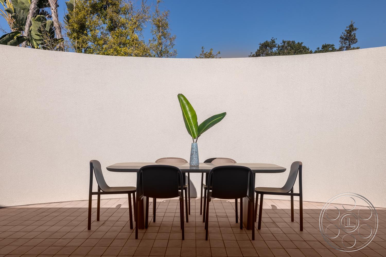 Modern 521 - curved wall design, terracotta tile flooring, contemporary outdoor seating, plaster wall finish, minimalist outdoor dining table, exterior dining area, arched overhead space, landscaped foliage view, decorative vase with greenery