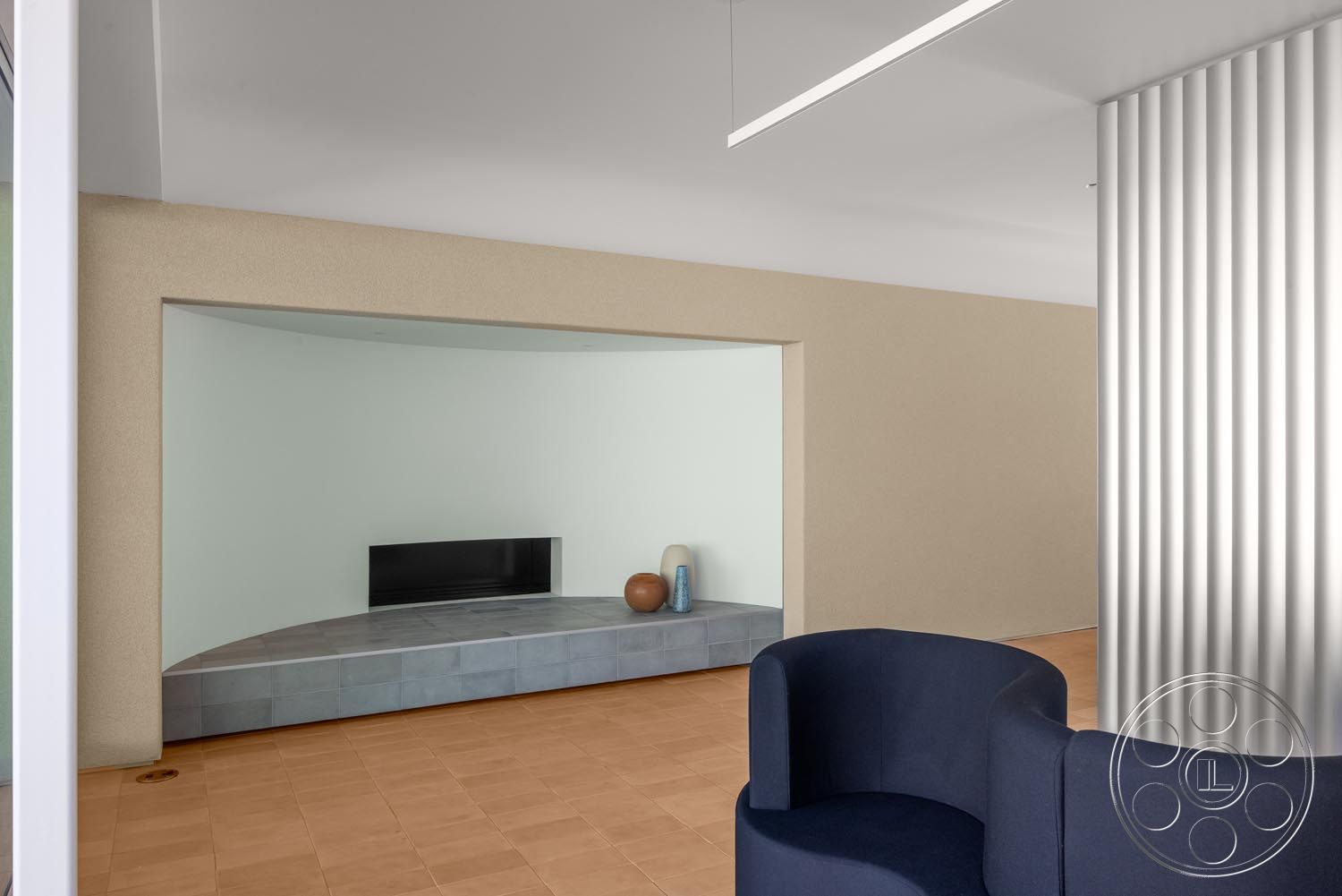 Modern 521 - neutral color palette, open-concept living space, natural light from large windows, interior minimalist design, smooth plaster wall finish, light wood paneling walls, curved feature wall with built-in seating, light gray ceramic tile flooring, tan rectangular floor tiles, modern linear LED lighting, black wall-mounted television, textured white ceiling, sculptural accent decor, soft geometric furniture shapes