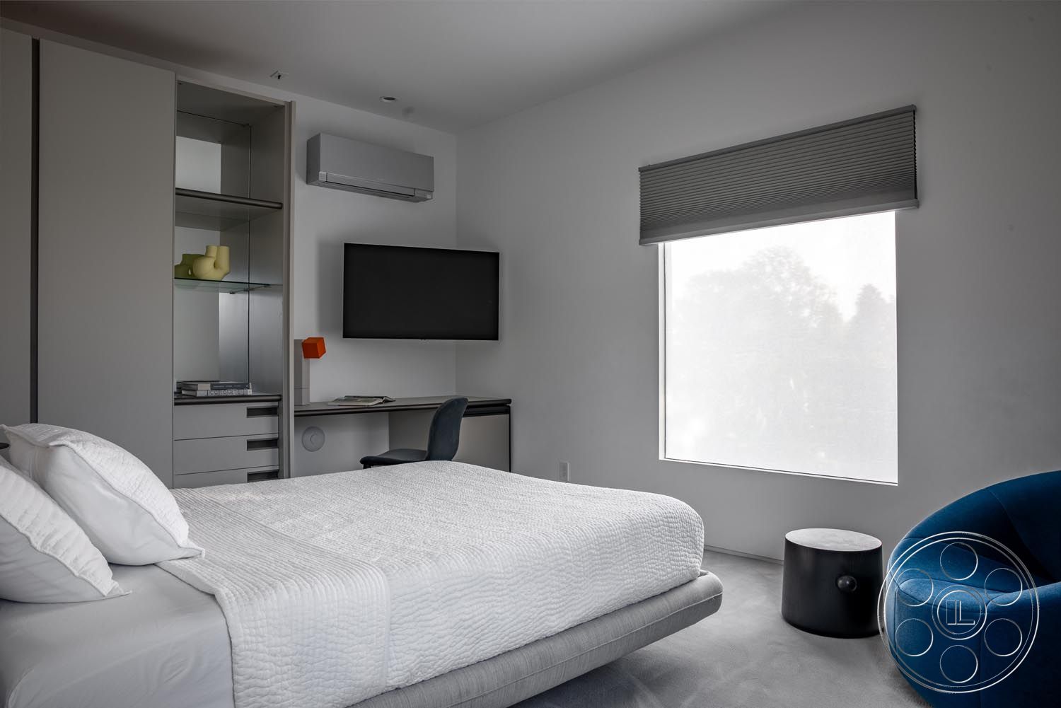 Modern 521 - textured wall finishes, neutral wall paint, horizontal window blinds, large picture window, minimalist nightstand, contemporary bedroom design, built-in shelving unit, light grey carpet flooring, wall-mounted flat-screen TV, glass display shelves, bedroom interior, white quilted duvet cover, plush upholstered bed frame, modern desk area with chair, orange wall accent lamp, soothing urban bedroom setting