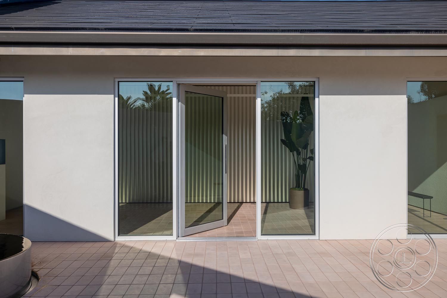 Modern 521 - exterior, open floor plan, large glass windows, glass sliding doors, paved walkway, horizontal ribbed wall treatment, minimalist architectural style, natural light emphasis, concrete patio floor, integrated indoor-outdoor living, modern flat roof, rectangular outdoor space, planted interior greenery, light-colored stucco exterior, contemporary entrance