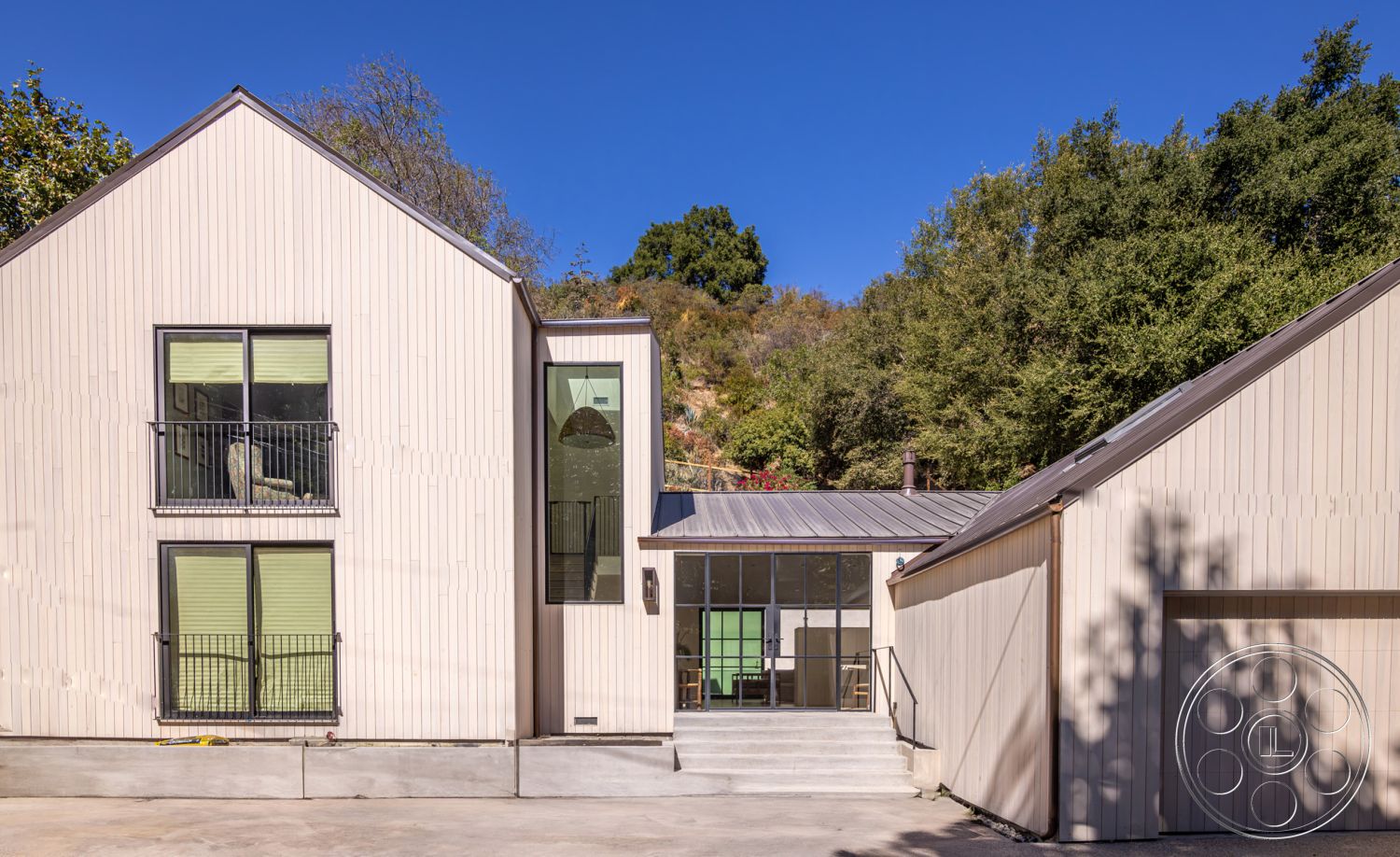 Modern Farmhouse 19 - metal roof, glass patio doors, rectangular windows, contemporary home design, textured wall details, exposed concrete steps, minimalist architectural style, urban hillside setting, surrounding hillside view, exterior wood panel siding, natural vegetation backdrop, balcony railing, sloped terrain landscaping, open exterior space, green accent windows, modern garage, split-level home