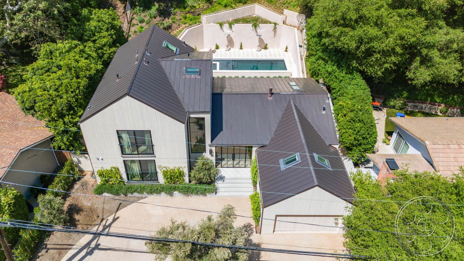 Modern Farmhouse 19 - large glass windows, outdoor seating area, surrounding greenery, exposed concrete walls, rectangular swimming pool, modern architectural style, paved pathways, asphalt driveway, poolside lounge chairs, urban residential setting, landscaped garden area, concrete patio flooring, rustic outdoor furniture, exterior metal roof, exterior vertical wood siding, two-story home design, plain concrete pool border, wooden deck leading to pool