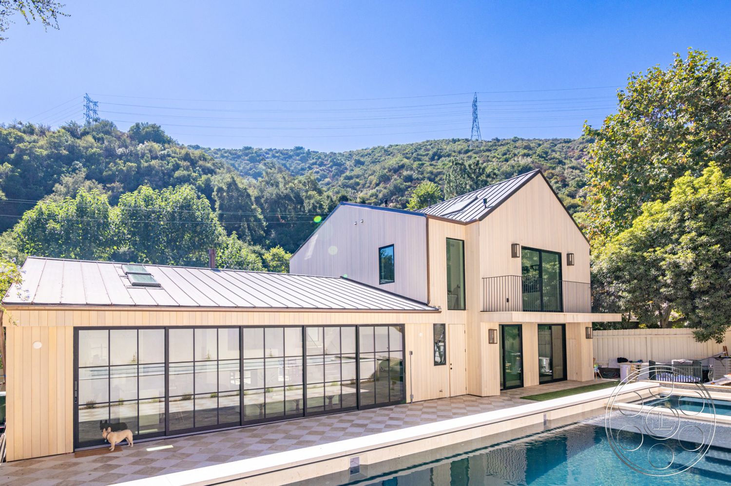 Modern Farmhouse 19 - glass sliding doors, outdoor seating area, textured concrete walls, rectangular swimming pool, floor-to-ceiling windows, geometric landscaping, mountain backdrop, open-concept layout, concrete pool deck, natural wood texture, landscaped garden area, stone patio flooring, modern architectural design, urban hillside setting, metal roof panels, exterior wooden siding, vaulted ceilings, balcony with metal railings, large rooftop skylights, horizontal siding details