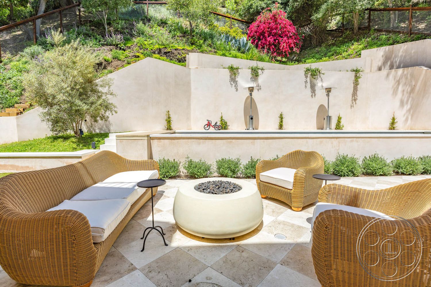 Modern Farmhouse 19 - exterior, clean lines, lush greenery, minimalist design elements, contemporary outdoor furniture, flowering plants, soft color palette, outdoor living area, serene retreat, ambient lighting fixtures, sunny outdoor patio, natural stone patio flooring, woven rattan chairs, rectangular fire pit, private backyard space, textured stucco wall, landscape garden setting, soft white cushions, water feature with wall