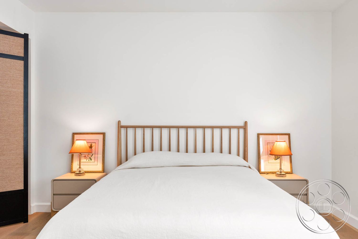 Modern Farmhouse 19 - minimalist decor, spacious layout, soft natural lighting, wood bed frame, white painted walls interior, neutral bedding, modern nightstands, laminate hardwood bedroom floors, table lamps with orange shades, framed artwork above nightstands, black sliding door with woven panel