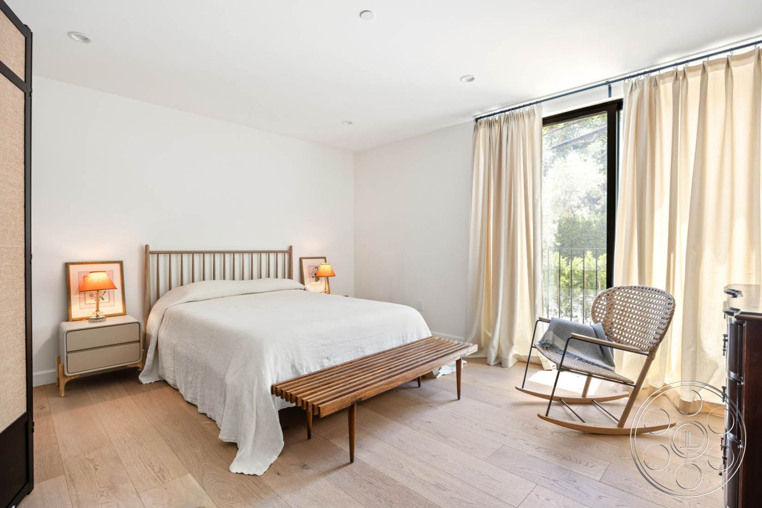 Modern Farmhouse 19 - neutral color palette, minimalist design, sheer curtains, large glass windows, decorative wall art, bright and airy atmosphere, contemporary interior, wood bed frame, hardwood bedroom floors, white painted walls, natural light throughout, interior lighting fixtures, modern rocking chair, bedroom with king-size bed, textured fabric bedspread, nightstand with lamps, wooden bench at foot of bed, room with balcony access