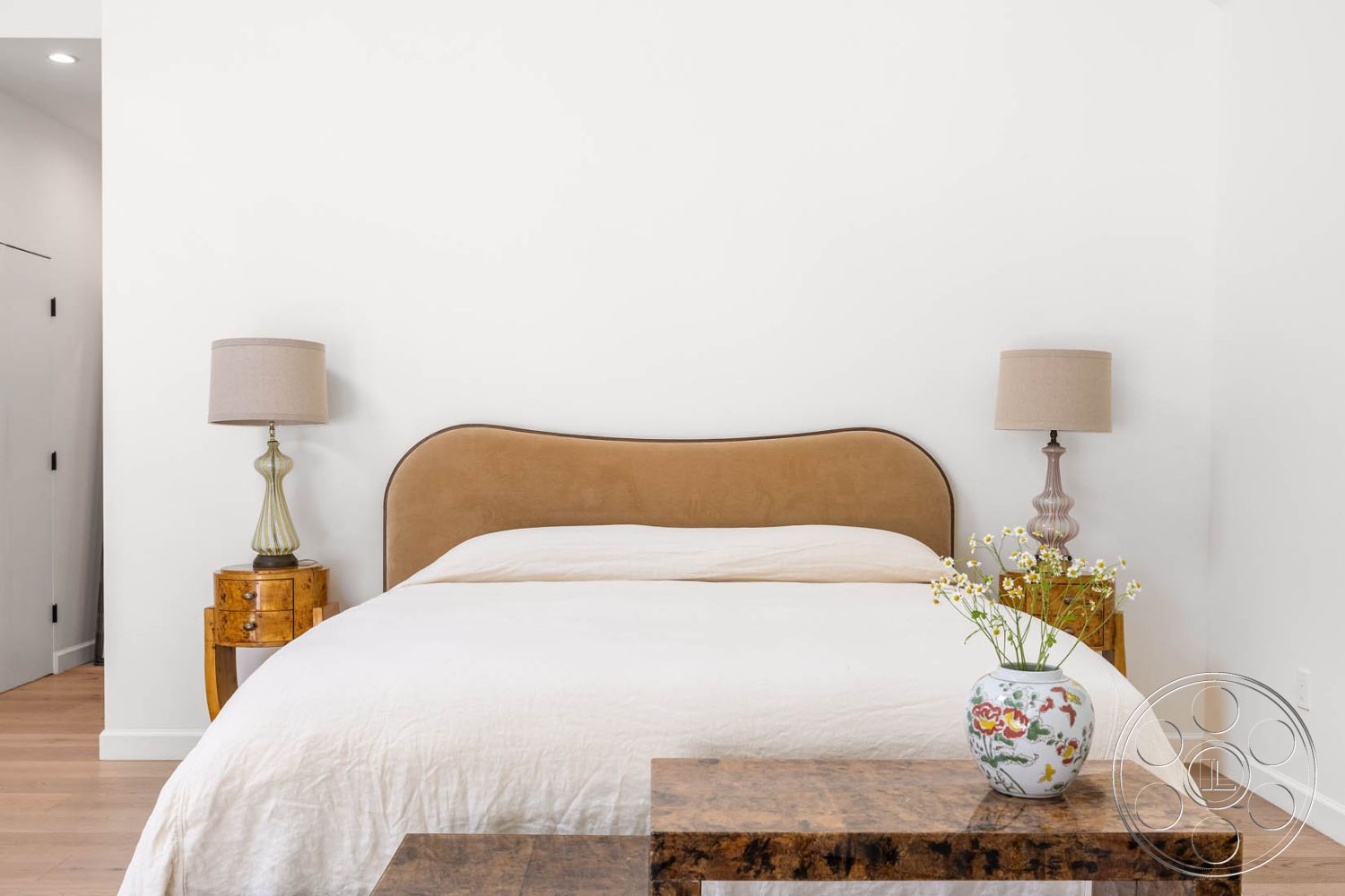 Modern Farmhouse 19 - neutral color palette, textured bedding, open space layout, soft lighting fixtures, cozy bedroom atmosphere, white painted walls, modern decorative accents, minimalist nightstands, contemporary bedside lamps, plush suede bed headboard, light wood bedroom floor, glass vase with floral arrangement, sleek table design