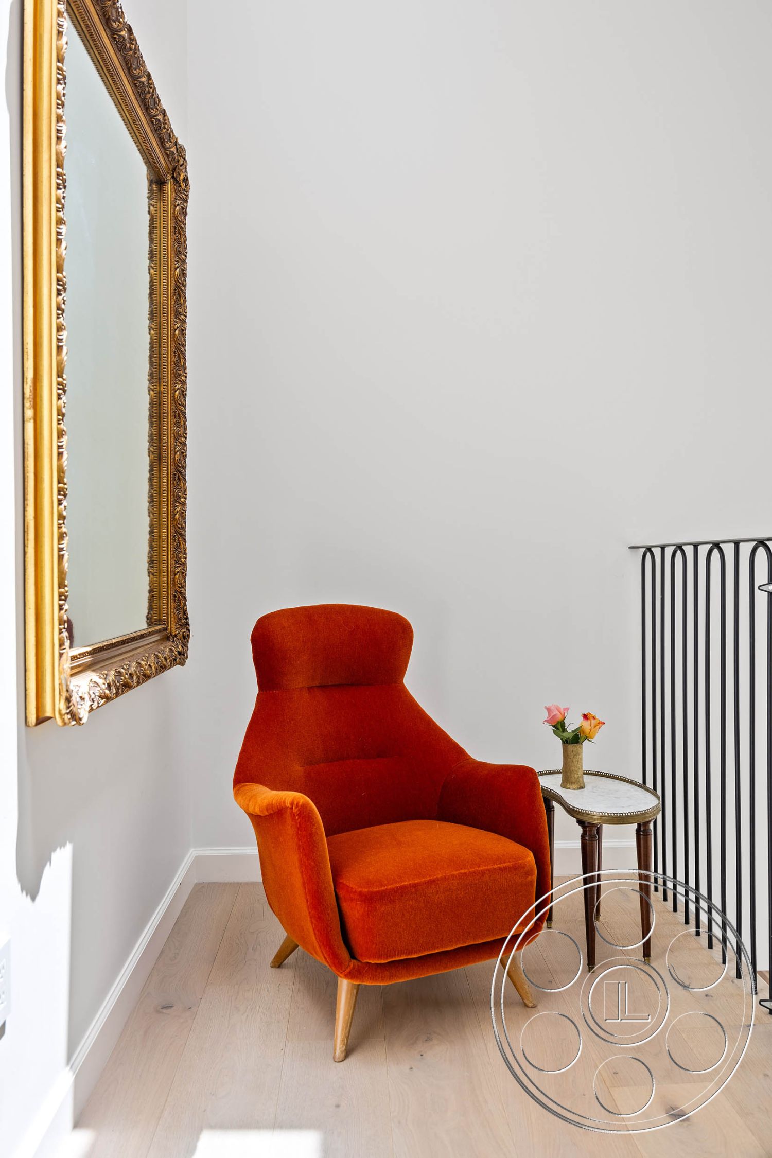 Modern Farmhouse 19 - interior minimalist decor, interior modern design elements, interior black metal railing, interior open space layout, interior bright natural light, interior light wood flooring, interior orange velvet accent chair, interior gold ornate framed mirror, interior wall-mounted flower vase