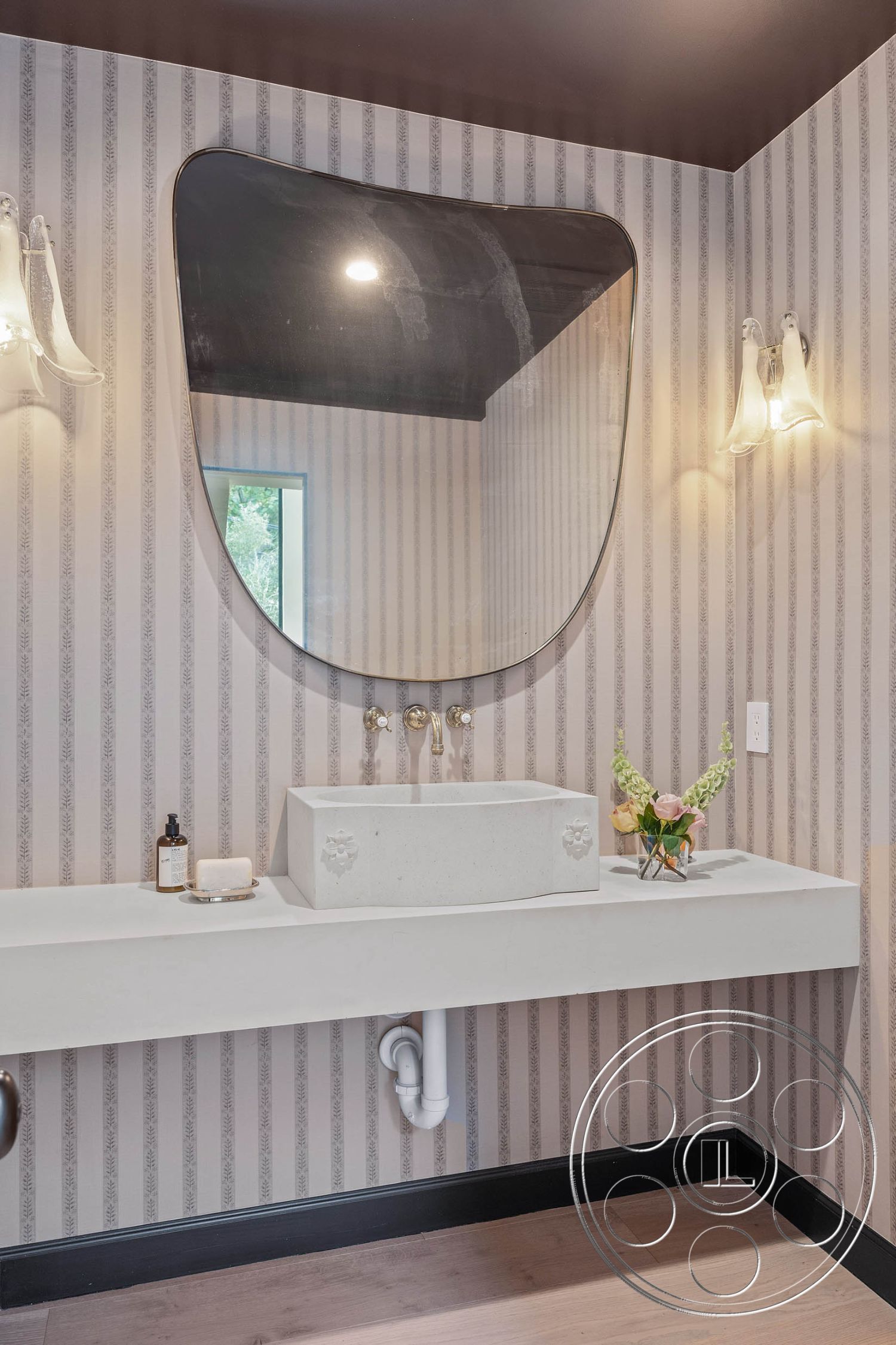 Modern Farmhouse 19 - exterior, contemporary aesthetic, concrete sink countertop, textured plaster bathroom walls, modern vessel sink, hardwood bathroom flooring, minimalistic bathroom design, black wood accent trim, curved mirror design, three-spout wall-mounted faucet, floral countertop arrangement, striped wallpaper accent, wall-mounted glass sconces