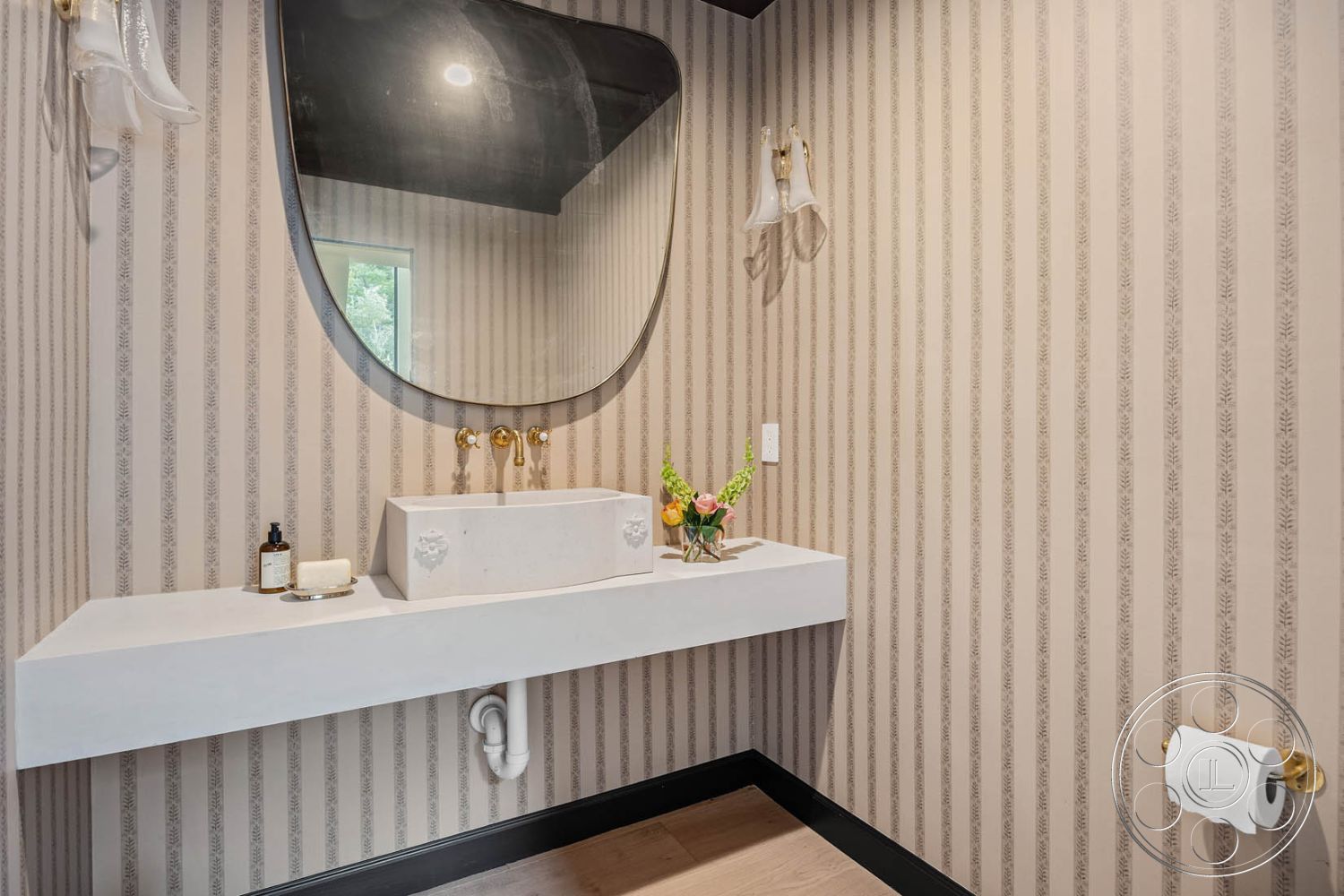 Modern Farmhouse 19 - modern design, light wood flooring, brushed gold faucets, minimalist style, striped wallpaper, interior bathroom, wall-mounted glass sconces, floating concrete countertop, oval wall mirror, black trim around fixtures