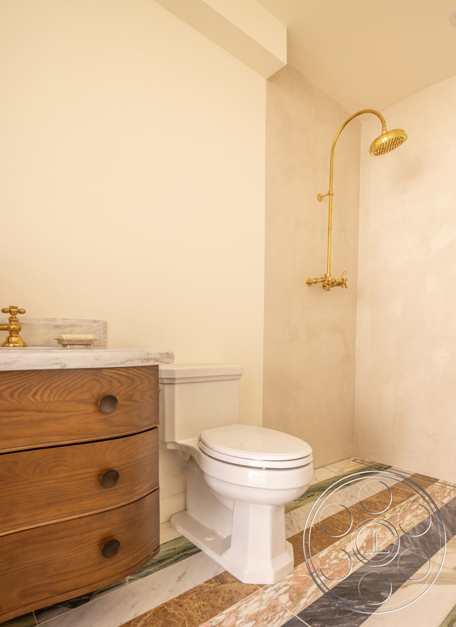 Modern Farmhouse 19 - white porcelain toilet, rectangular shower area, minimalist decor style, interior bathroom, textured plaster accent wall, marble vanity countertop, walnut bathroom cabinetry, gold brass shower fixtures, marble flooring with geometric pattern, floor-to-ceiling showerhead, clean-lined contemporary design