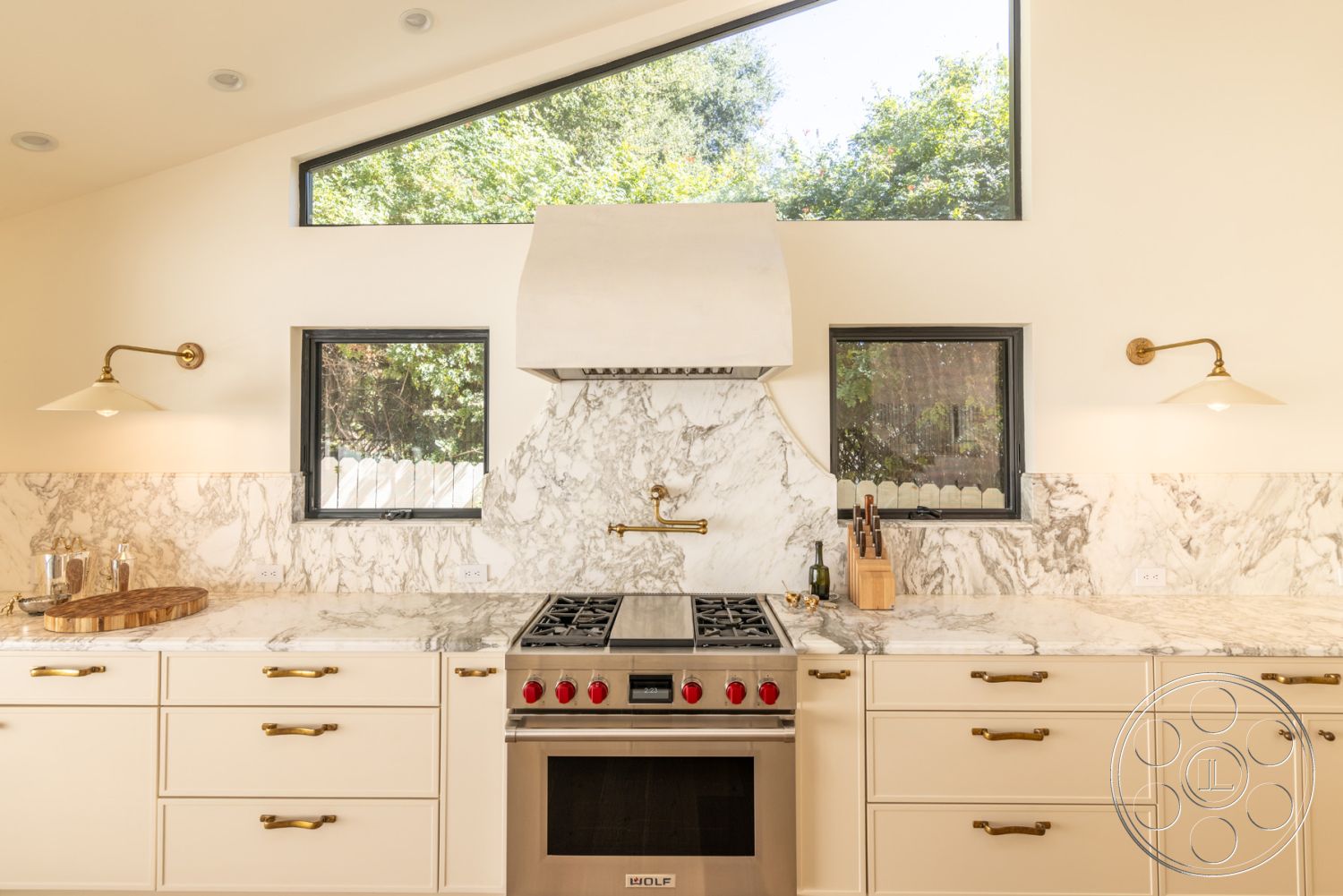 Modern Farmhouse 19 - minimalist design elements, open-concept layout, brass wall sconces, modern kitchen appliances, interior kitchen with marble countertops, natural light-filled space, exposed window frames, white cabinetry with brass hardware, marble backsplash with integrated hood, geometric skylight windows, subtle warm color palette, contemporary fixture design