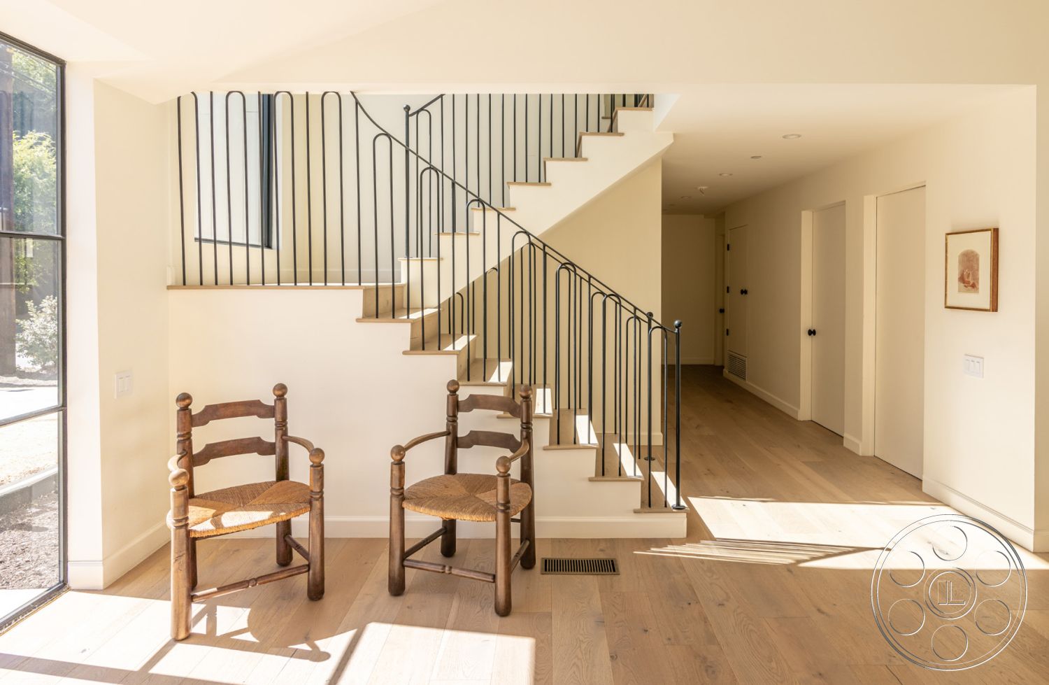 Modern Farmhouse 19 - neutral color palette, minimalist design, open floor plan, natural wood beams, textured wall paneling, spacious foyer, double door entry, modern seating area, natural light interior, interior hardwood flooring, window with garden view, shiplap wall treatment, black steel railings, contemporary art on wall, subtle architectural details, exposed steel staircase, sunlit entryway, simple wooden chairs